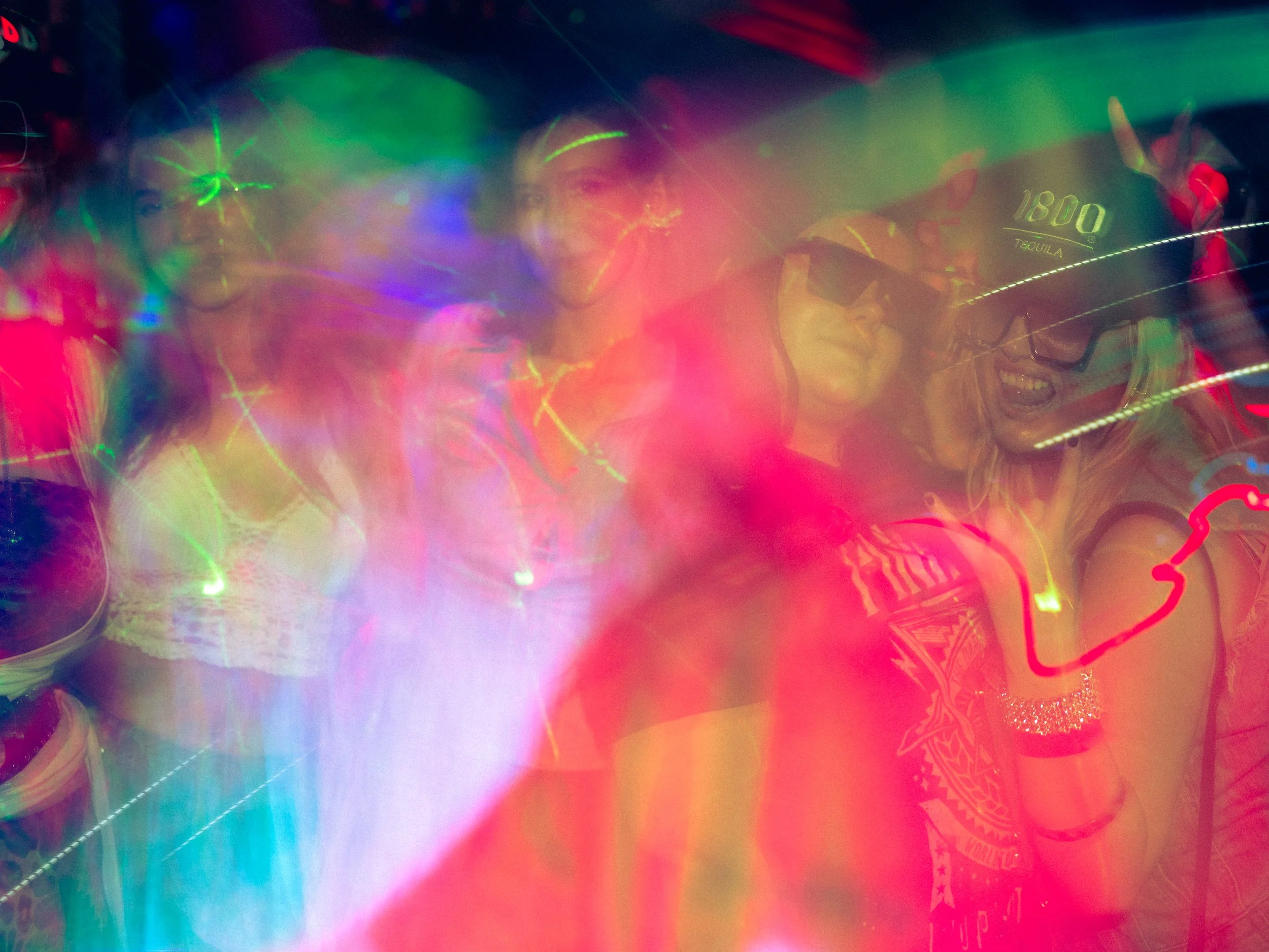 Group of people at a party or nightclub with colorful lights and motion blur.