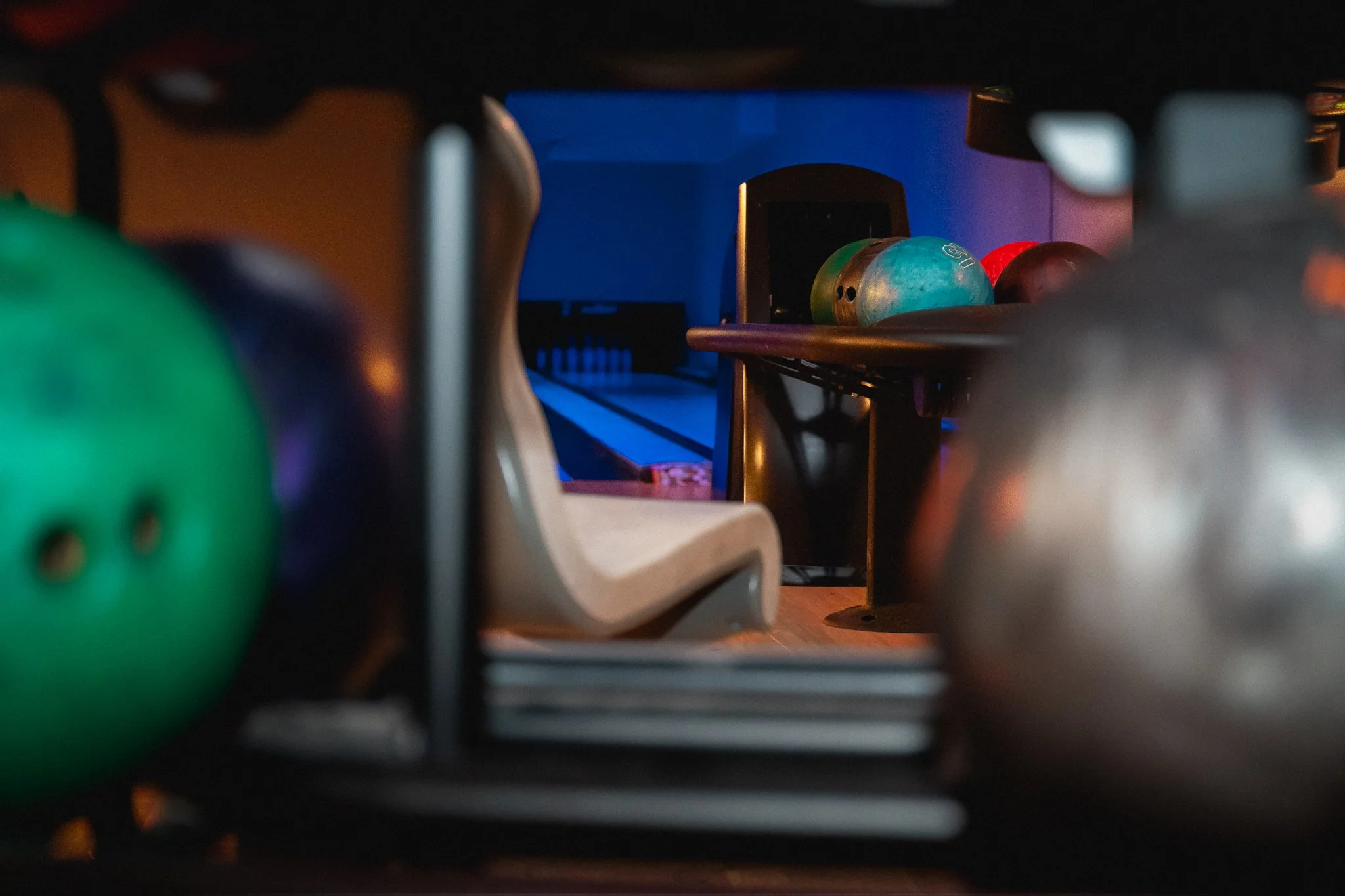 Bilde av bowlingkuler på en bowlingbane med en skjenk i bakgrunnen, sett gjennom en ramme