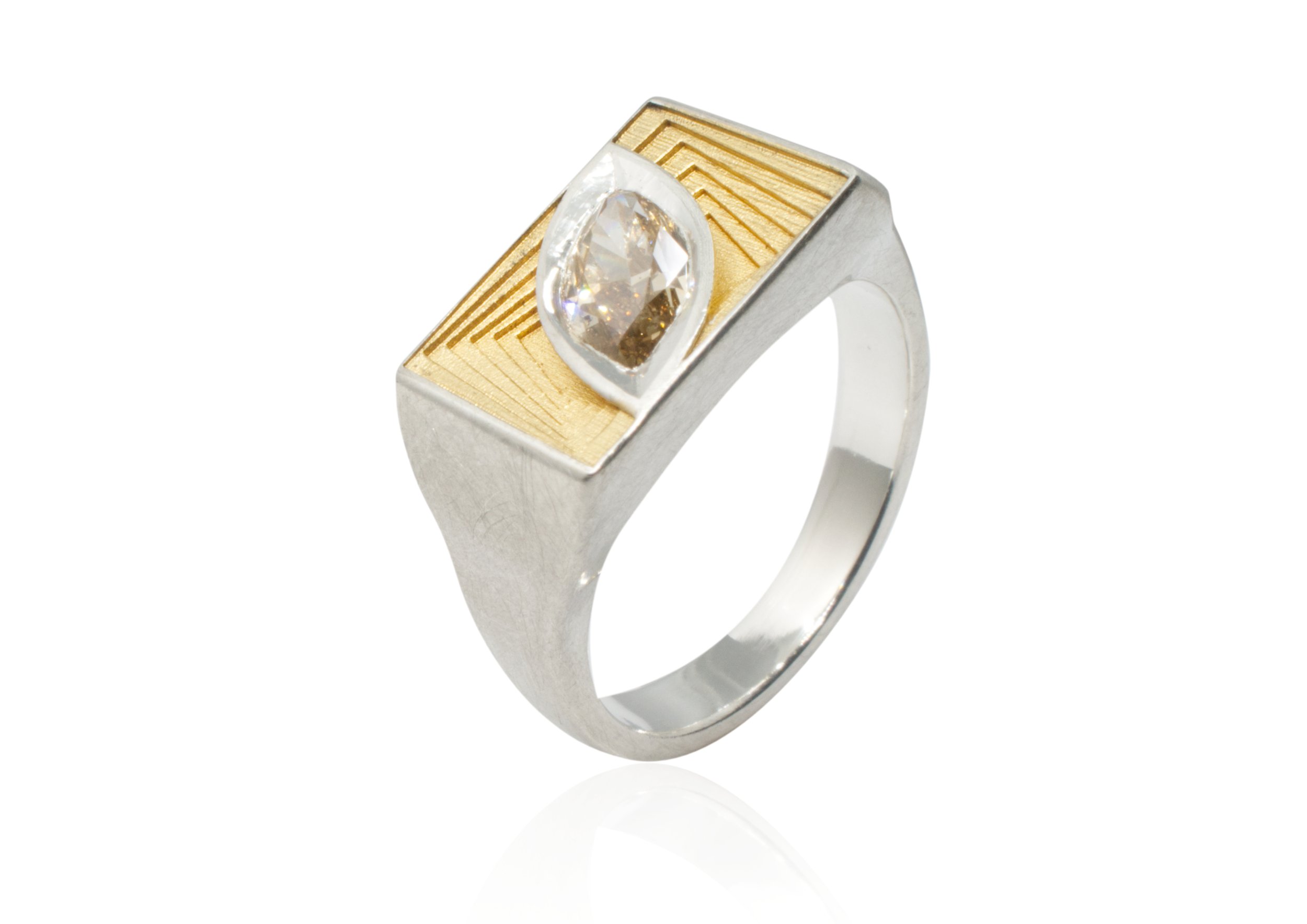 A modern silver ring with a large clear gemstone set in a rectangular gold detailing on the top surface.