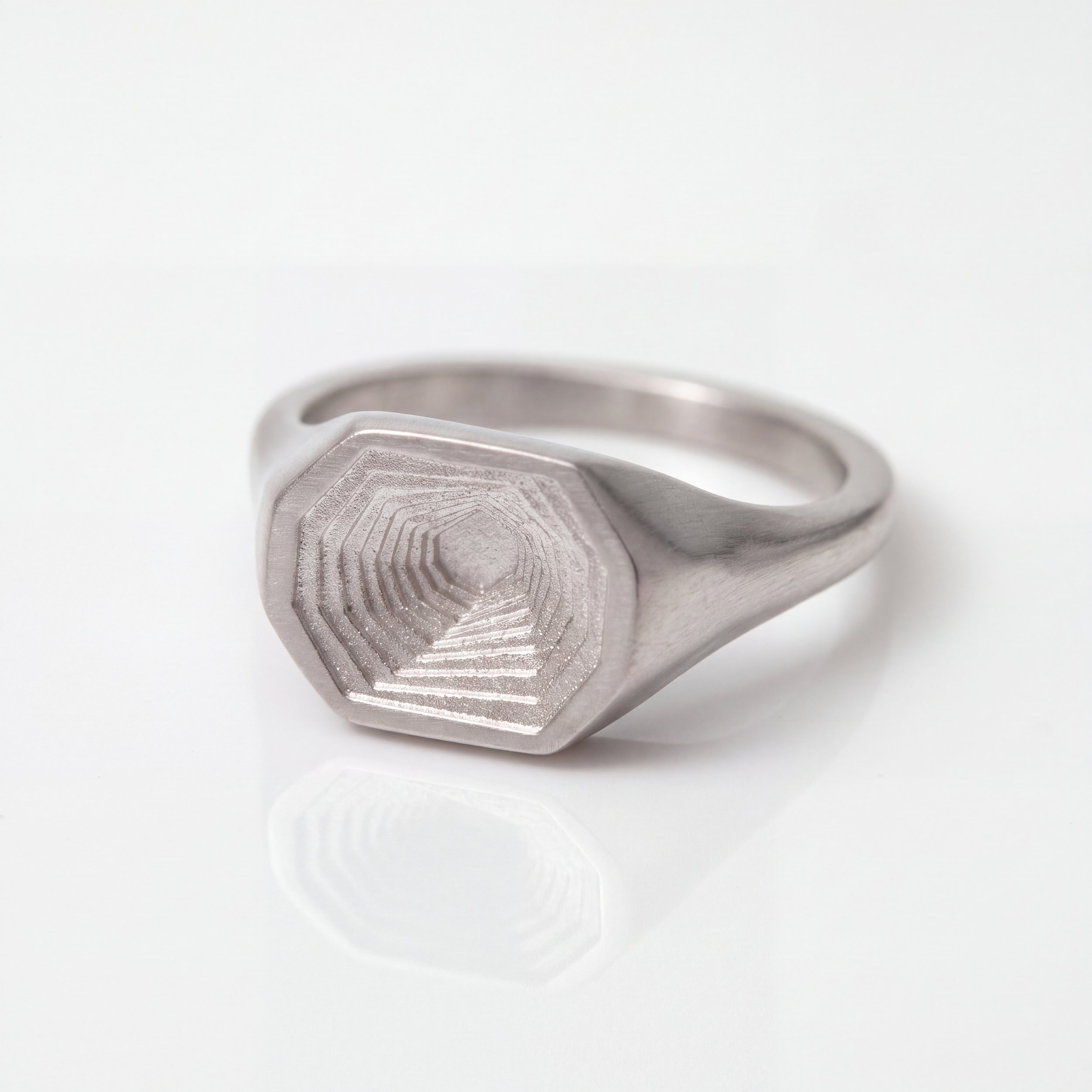 A modern silver ring with a large clear gemstone set in a rectangular gold detailing on the top surface.