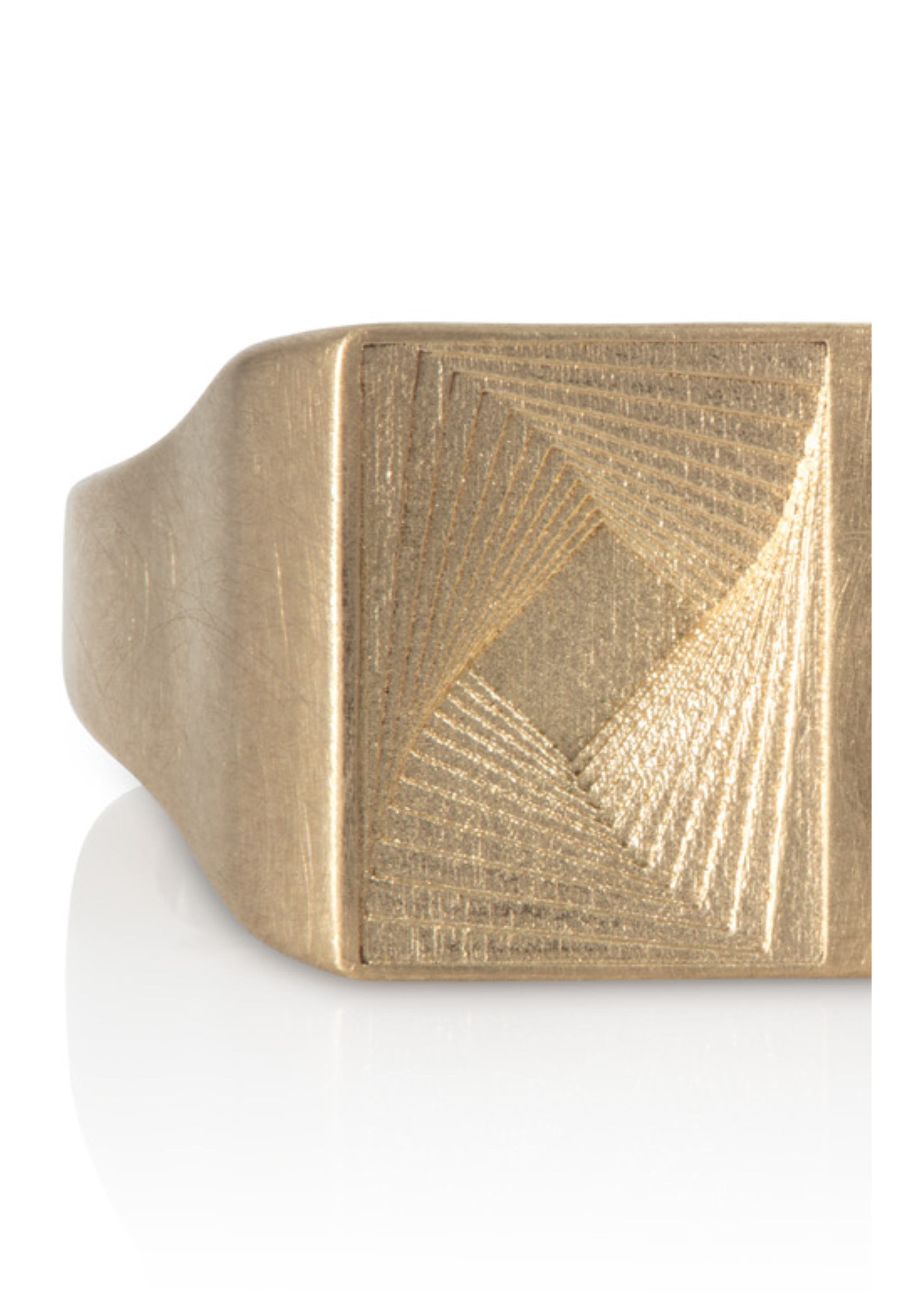 Close-up of a gold-colored ring with a square face displaying intricate geometric patterns.