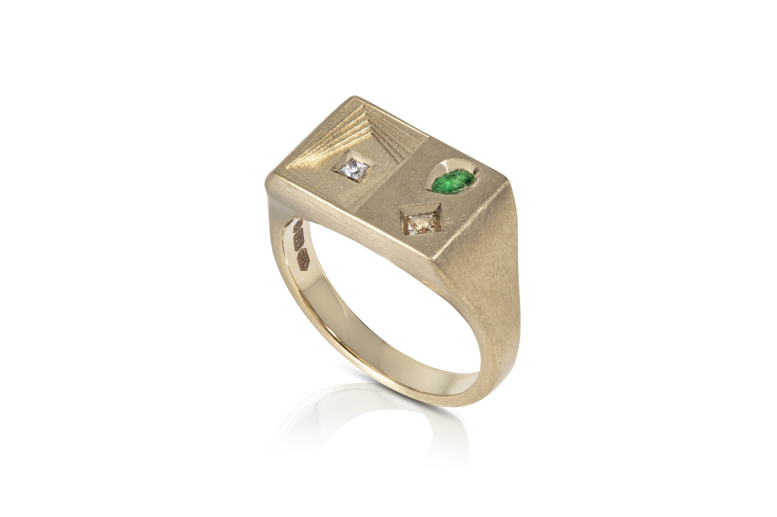 Gold ring with a rectangular top featuring two small diamonds and a small emerald set in a modern design.