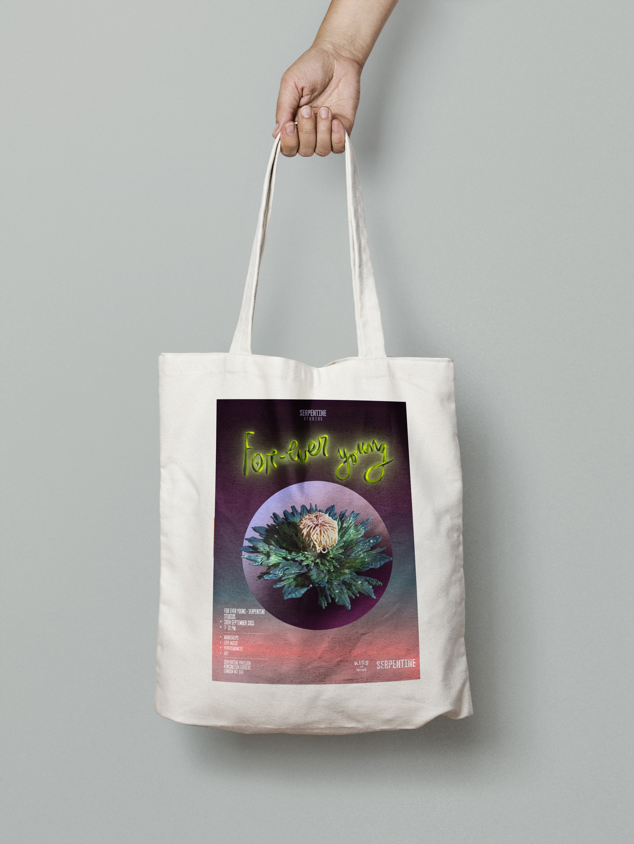 Person holding a white tote bag with a colorful graphic design and text.