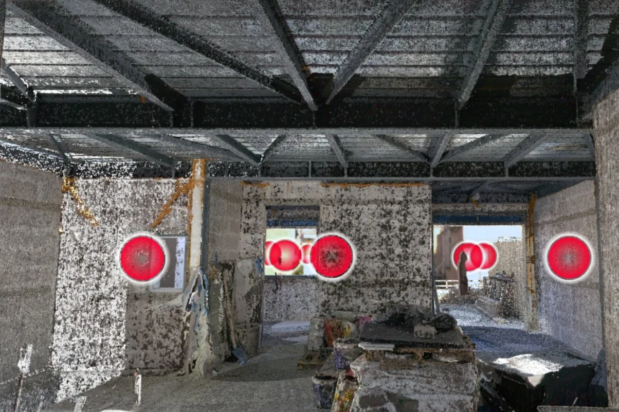 Construction site interior with exposed concrete walls and metal ceiling beams, red target markers on windows and wall, construction materials and tools scattered on the floor.
