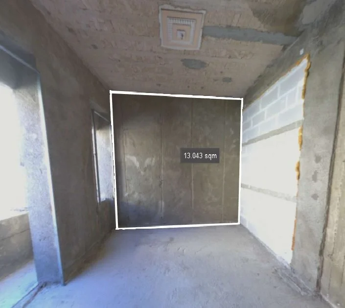 Empty room under construction with bare concrete walls, a partially cinder block wall, two small windows, a ceiling vent, and a floor with construction debris. The room is measured at 13.043 square meters.