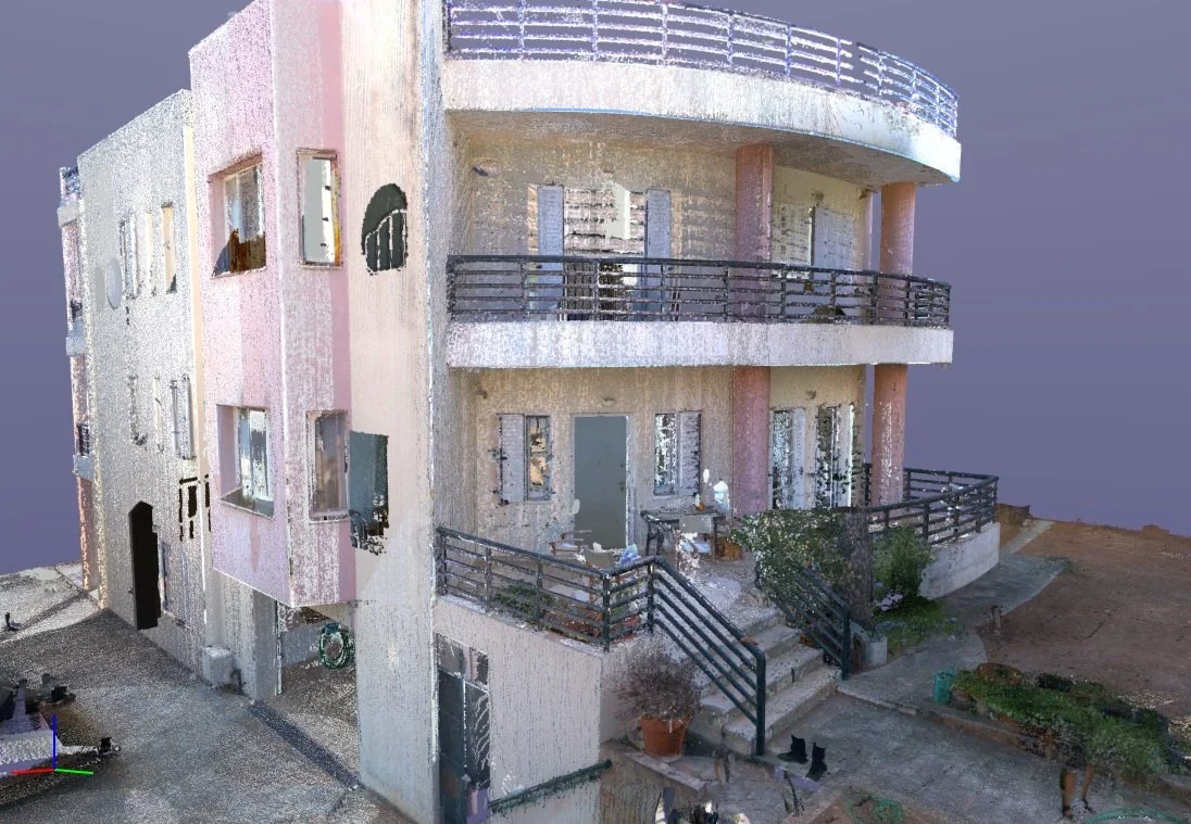 A multi-story apartment building with balconies, glass doors, and a few potted plants outside. The building has a light pink and beige exterior, with some areas looking weathered.