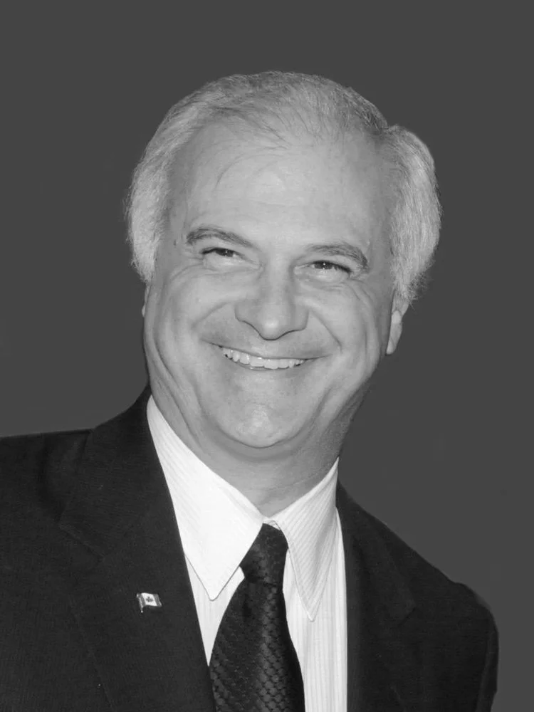 Black and white portrait of a smiling middle-aged man with gray hair, wearing a suit and tie.