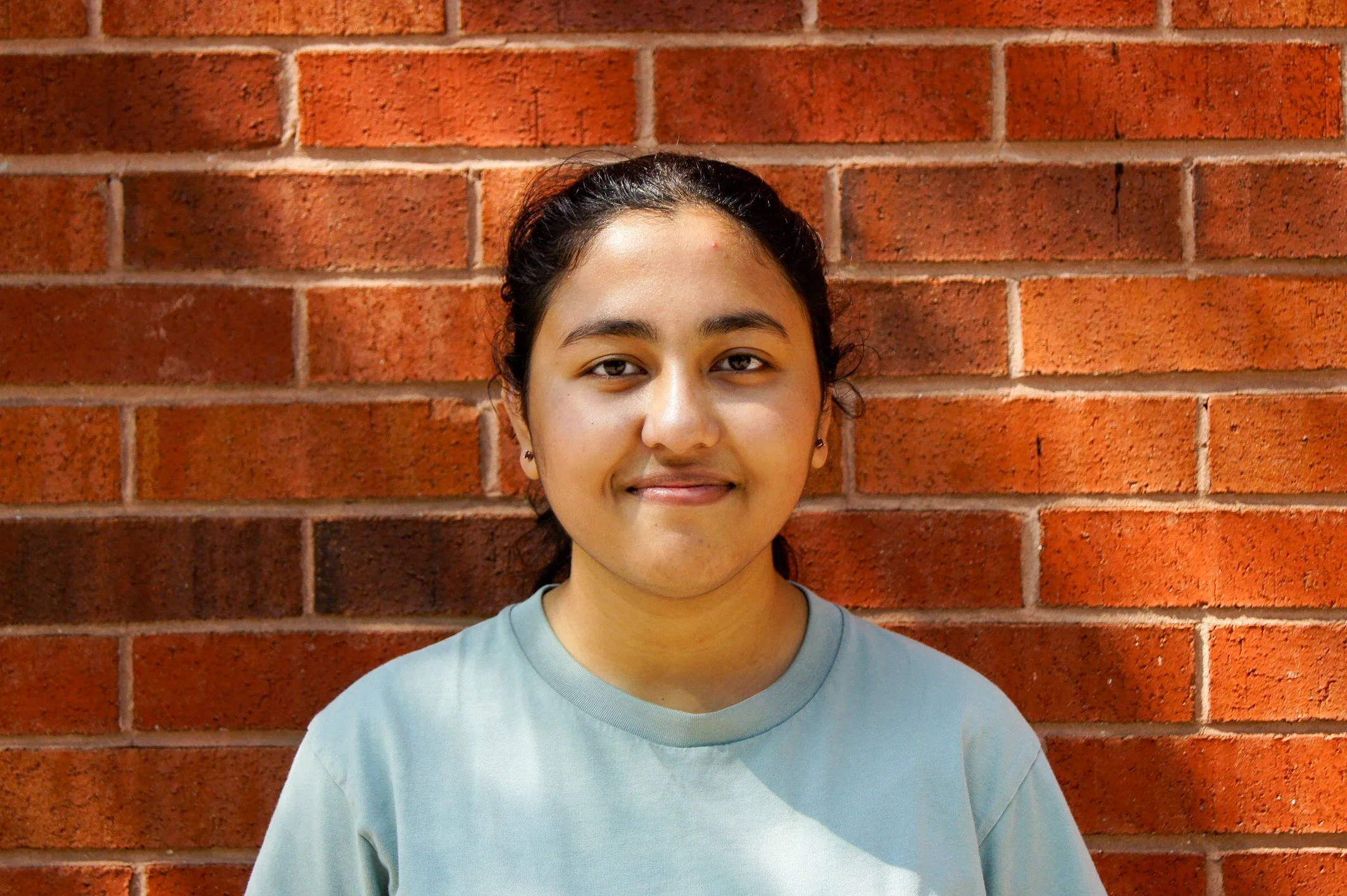 Smiling young woman against a breick wall