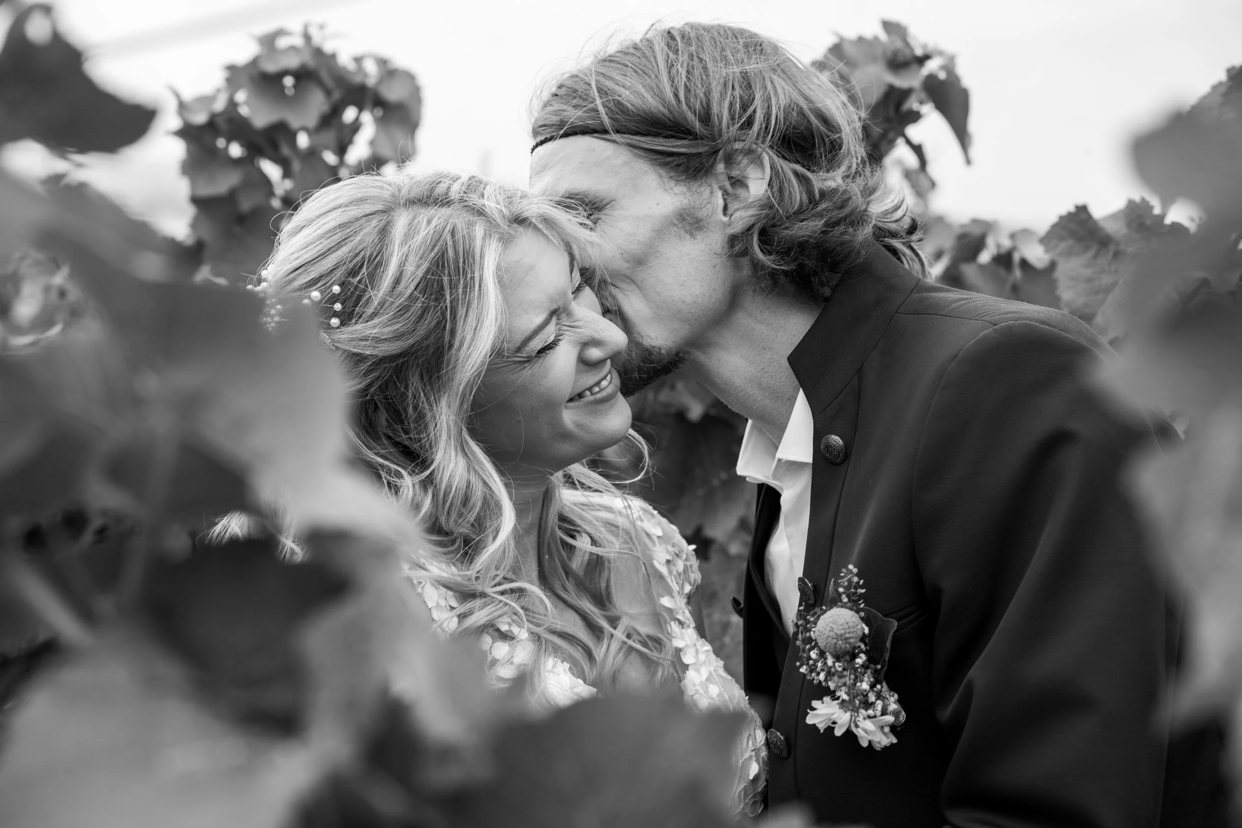 Ein glückliches Paar in einer Weinberg-Umgebung bei einer Hochzeitsaufnahme, die sich liebevoll berühren.