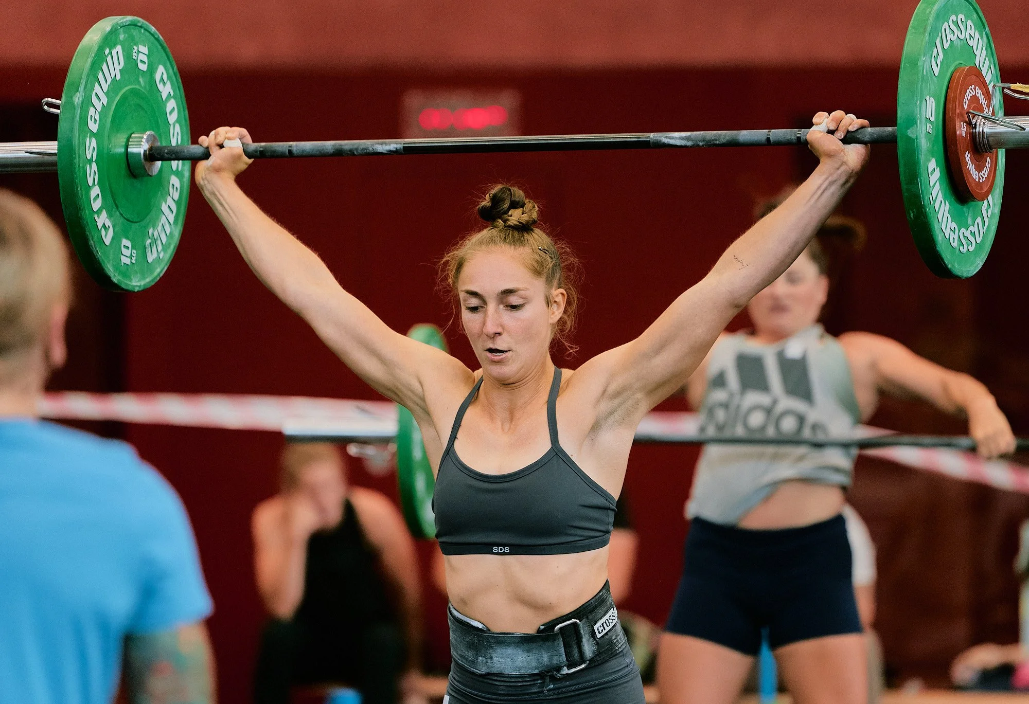 Fotograf & Videograf Wil SG Ostschweiz Daniel Dorrer Frau beim Gewichtheben, hebt eine Langhantel über den Kopf, trägt Sportbekleidung in einem Fitnessstudio.