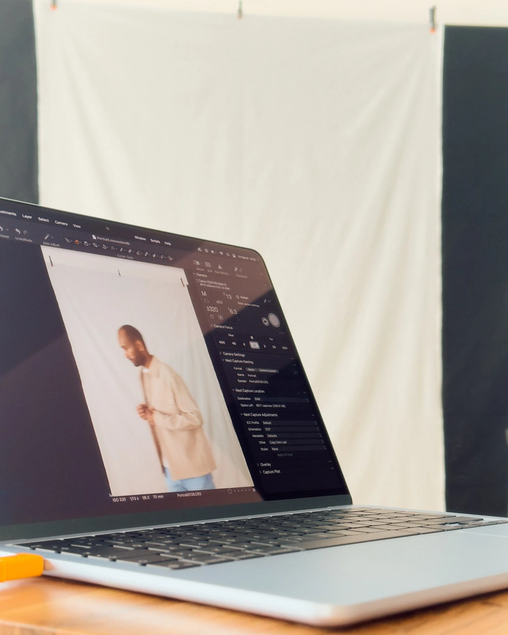 Ein Laptop auf einem Tisch mit einem Bild des Models auf dem Bildschirm, hinter einem weißen Hintergrund.