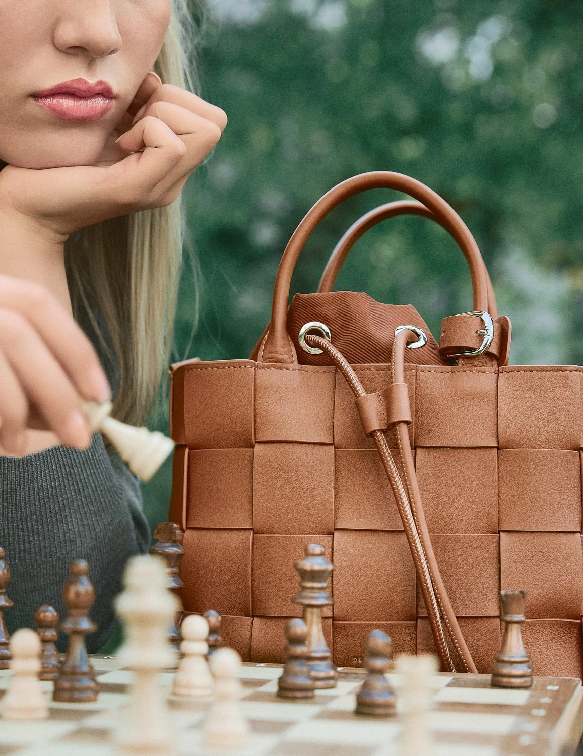 Nahaufnahme eines Mädchens, das Schach spielt, mit einer braunen Handtasche im Hintergrund.