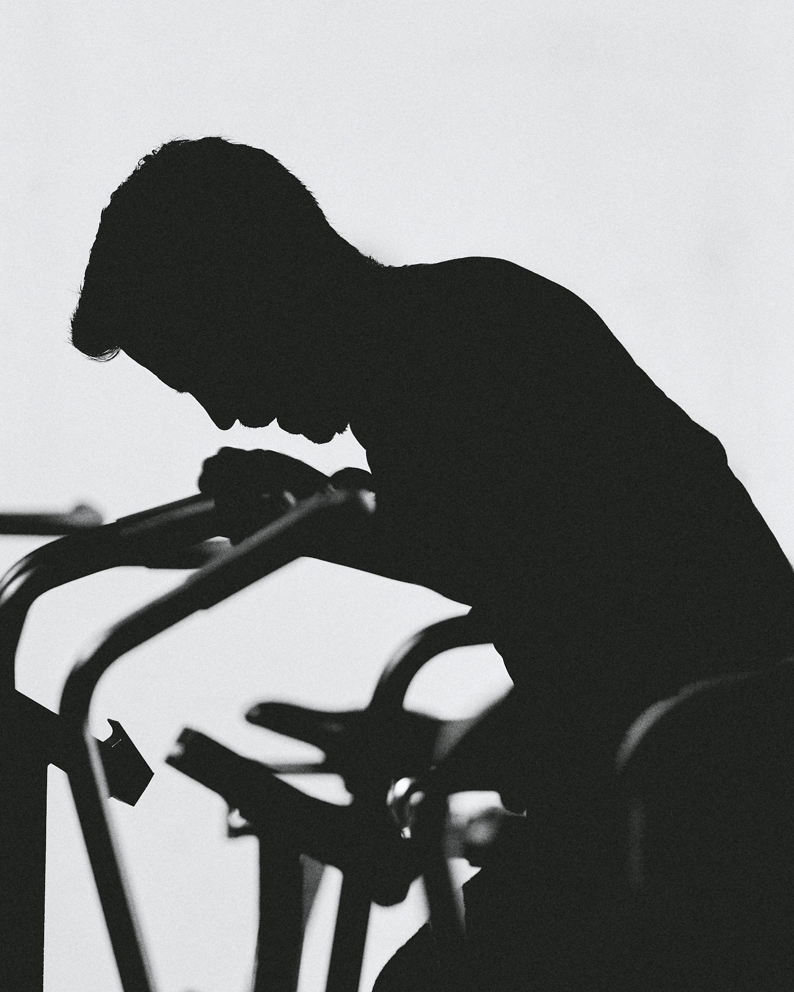 Fotograf & Videograf Wil SG | Businessfotografie Ostschweiz Daniel Dorrer Schwarz-weißer Silhouetten-Foto eines Kindes, das auf einem Fahrrad sitzt und nach unten schaut. Daniel Dorrer Film und Bild