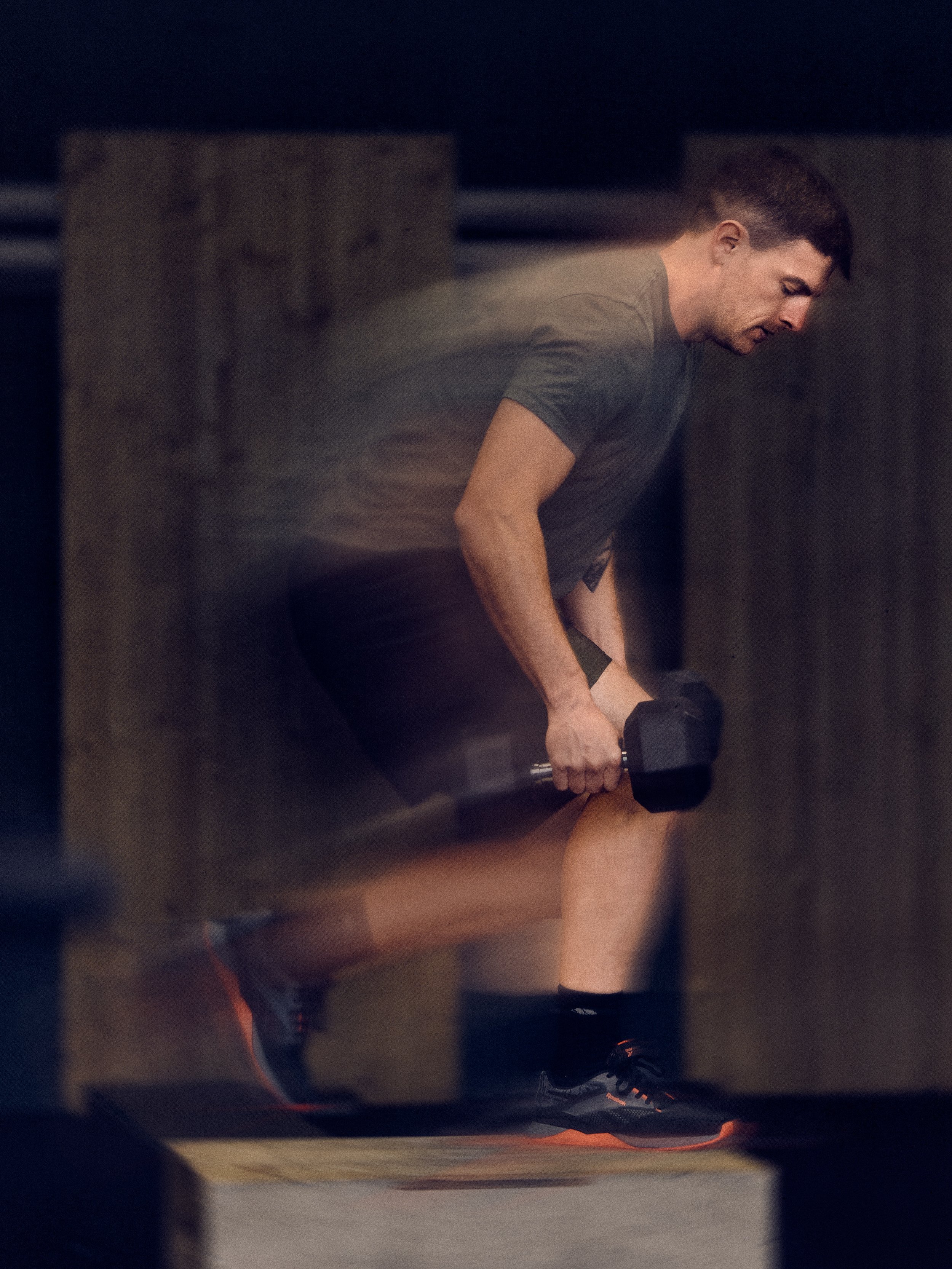Ein junger Mann beim Krafttraining mit Kurzhanteln in einem Fitnessstudio