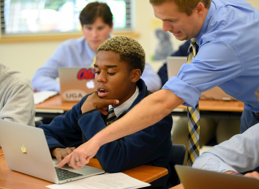 A photo of a teacher helping a student.