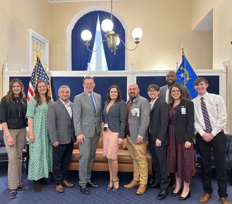 A photo of a group of leaders smiling in front of the USA flag.