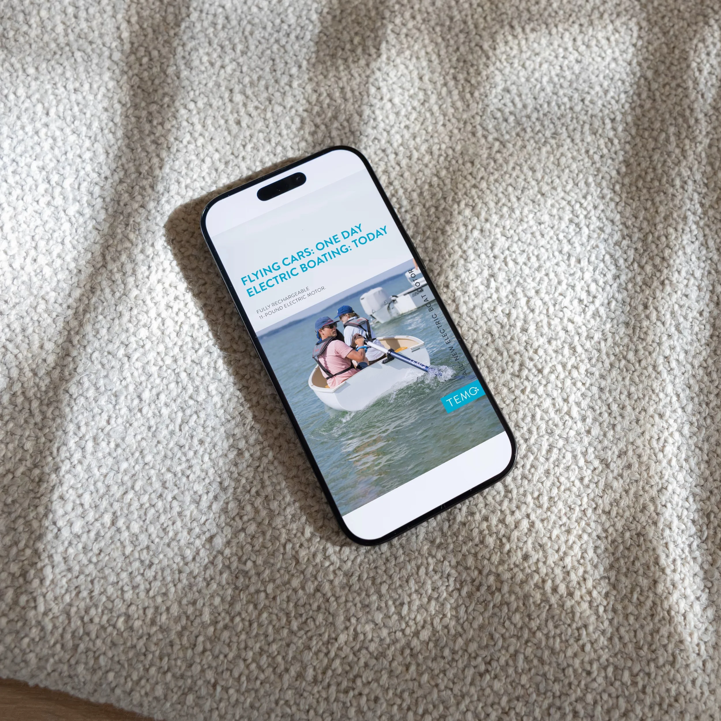 Smartphone displaying an advertisement for flying electric cars on a beige textured surface.