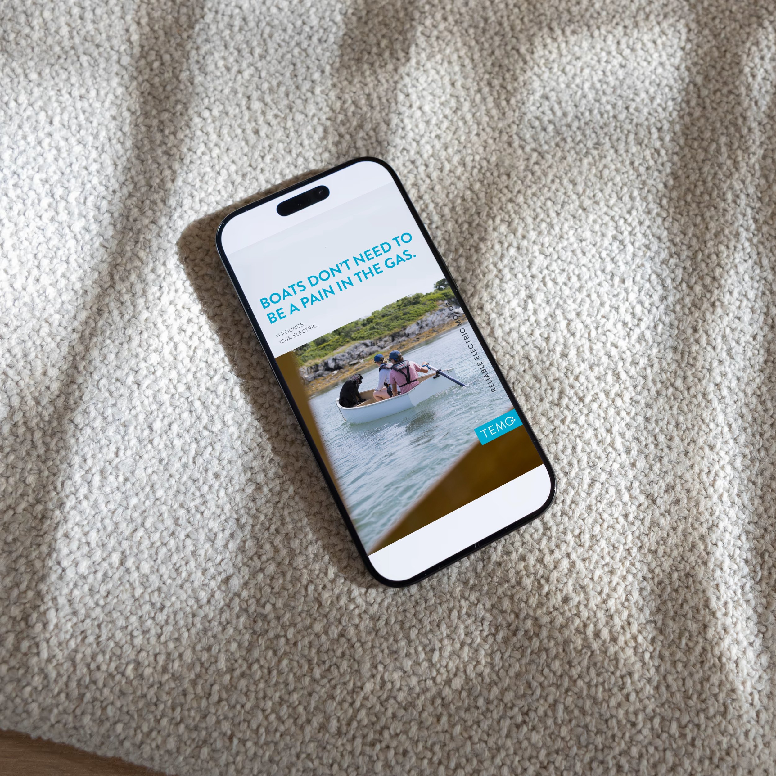 Smartphone displaying an advertisement for boats on a fluffy beige surface.