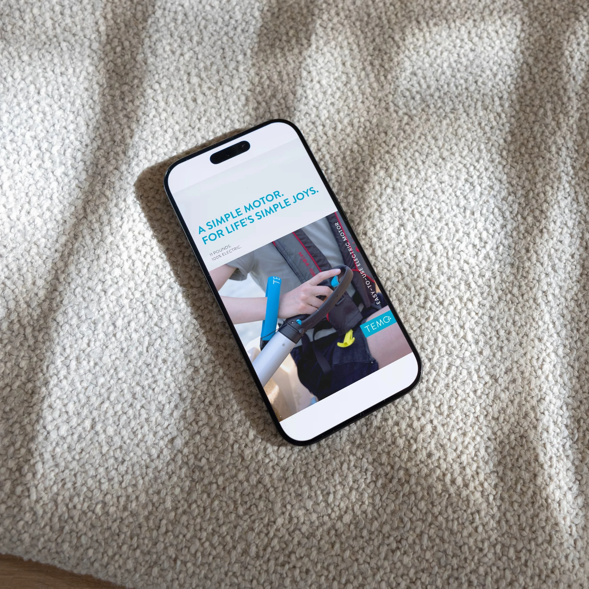 Smartphone displaying advertisement for a portable electric scooter on a beige textured fabric surface.