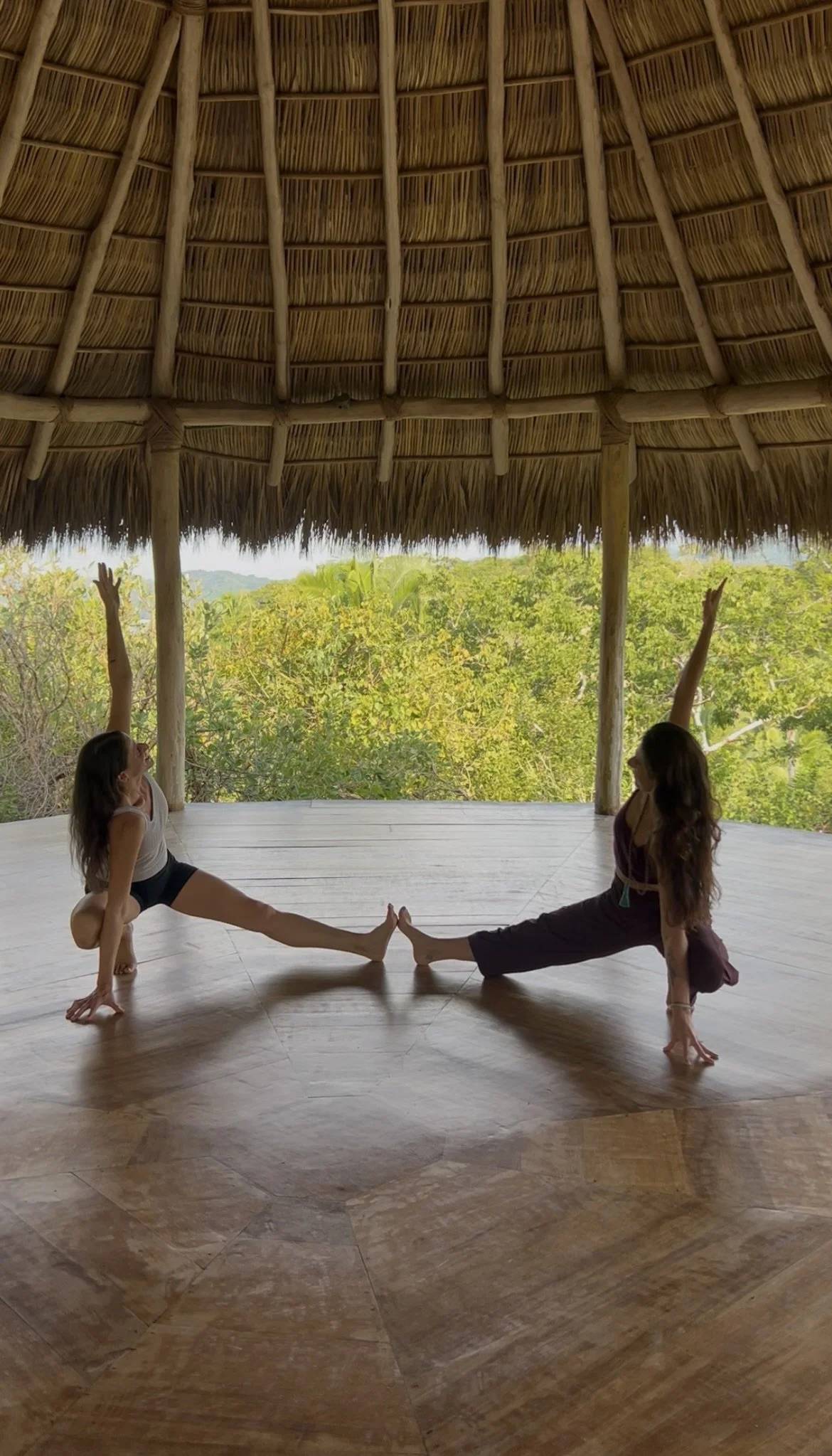 Two women in a yoga pose in a yoga shala in Mexico