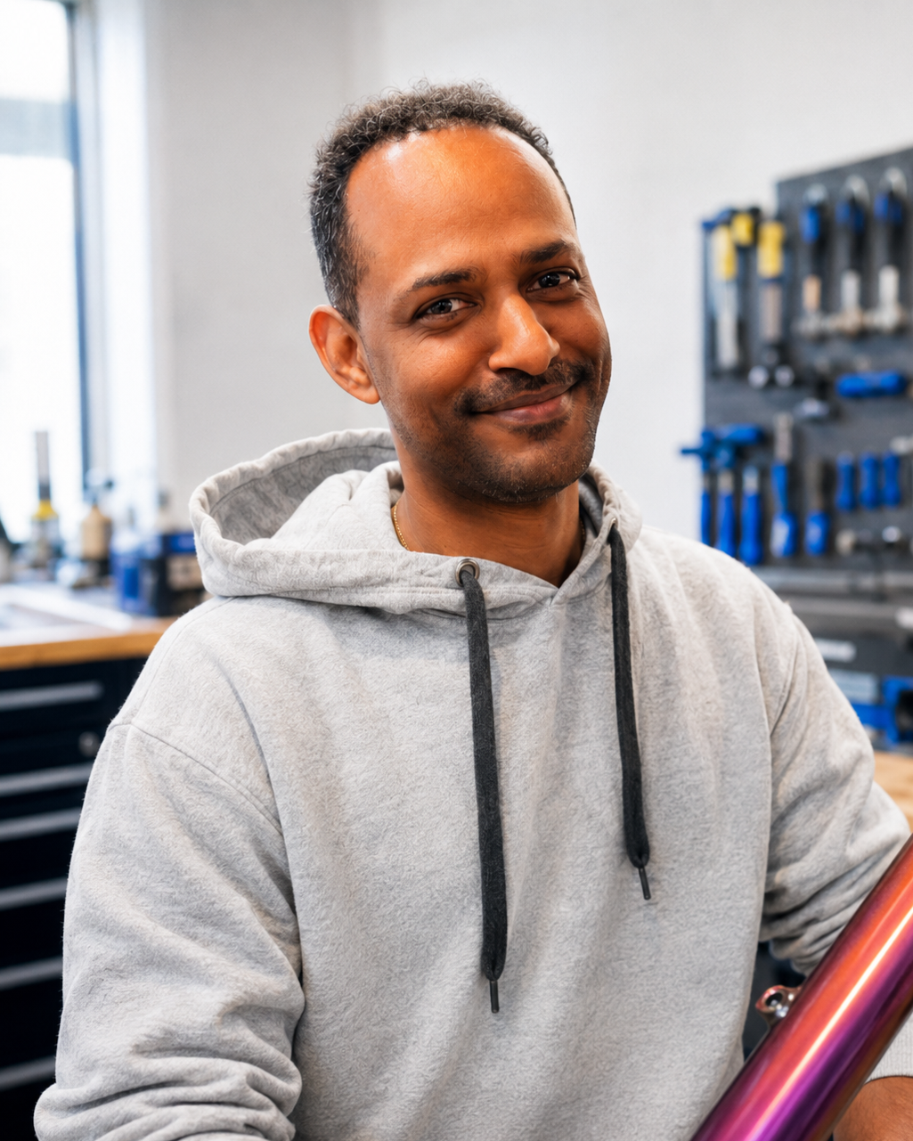 A man smiling and holding a colorful mountain bike frame indoors.