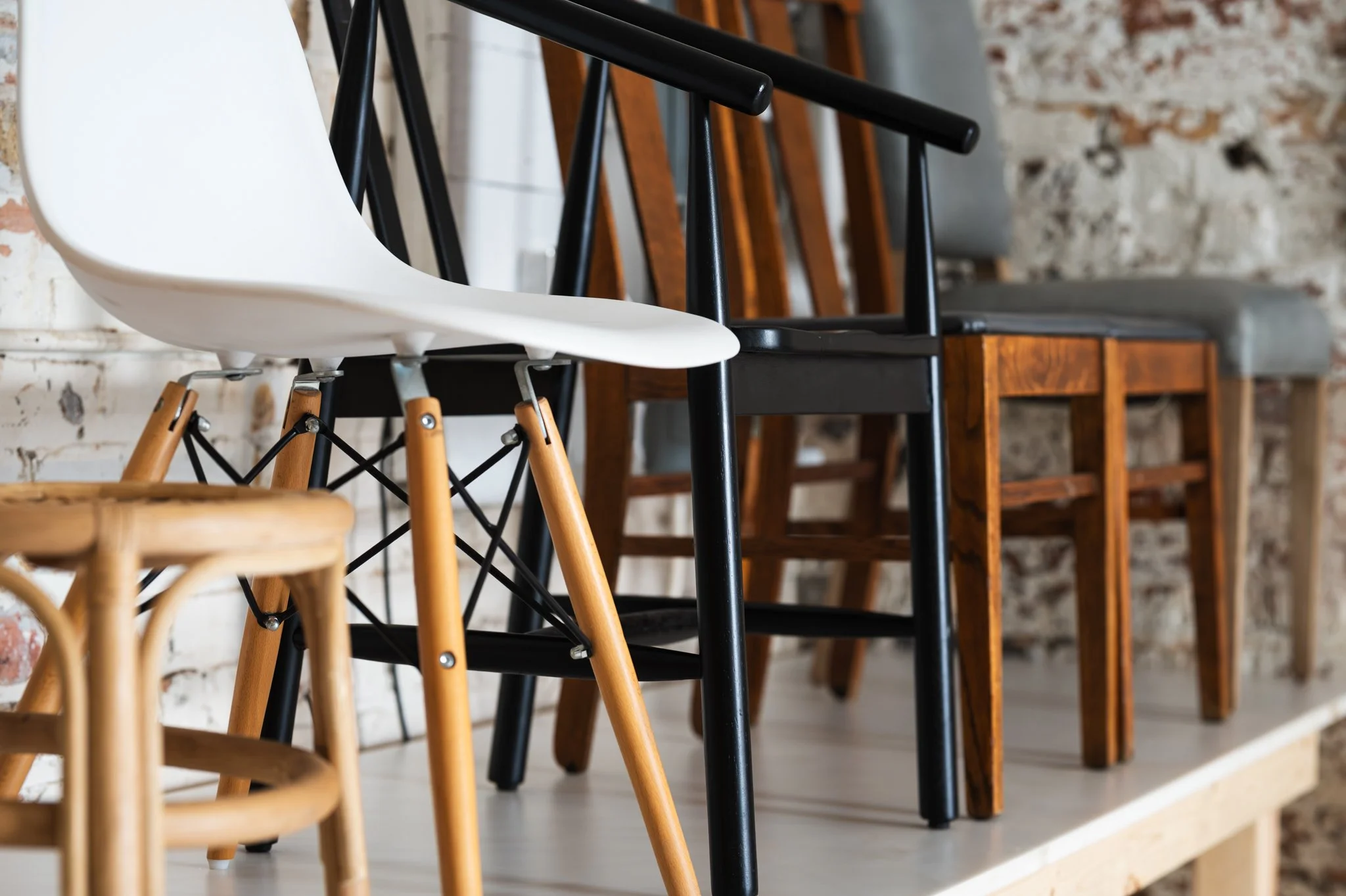 AH AH's props and a variety of chairs in different styles and colors are lined up against a textured brick wall.
