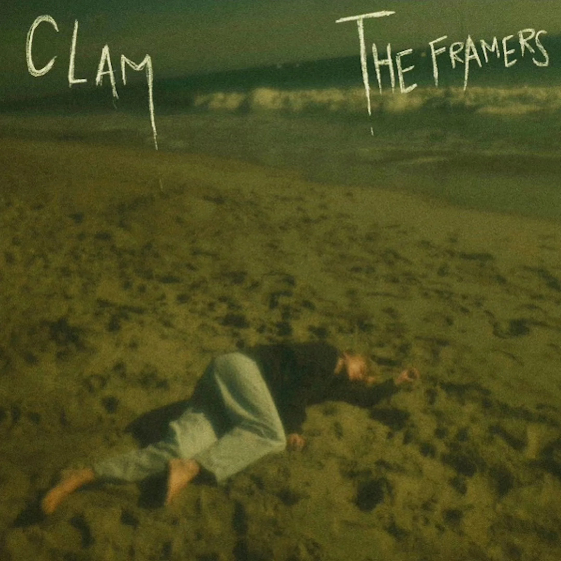 Person lying face down on sandy beach at night with handwritten words 'Clam' and 'The Framers' written in the sky. This is the cover art for a song named Clam, written and performed by The Framers.