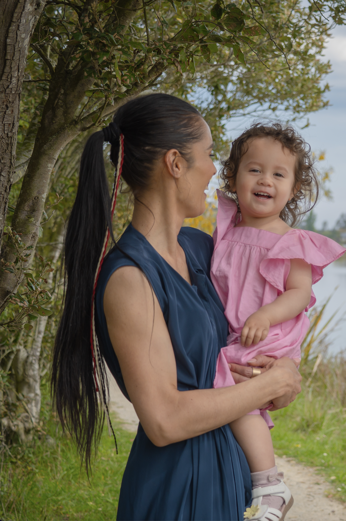 Kimberley Maaka holding her baby, reflecting the whānau and legacy behind Miro Locs muka harakeke fibre design.