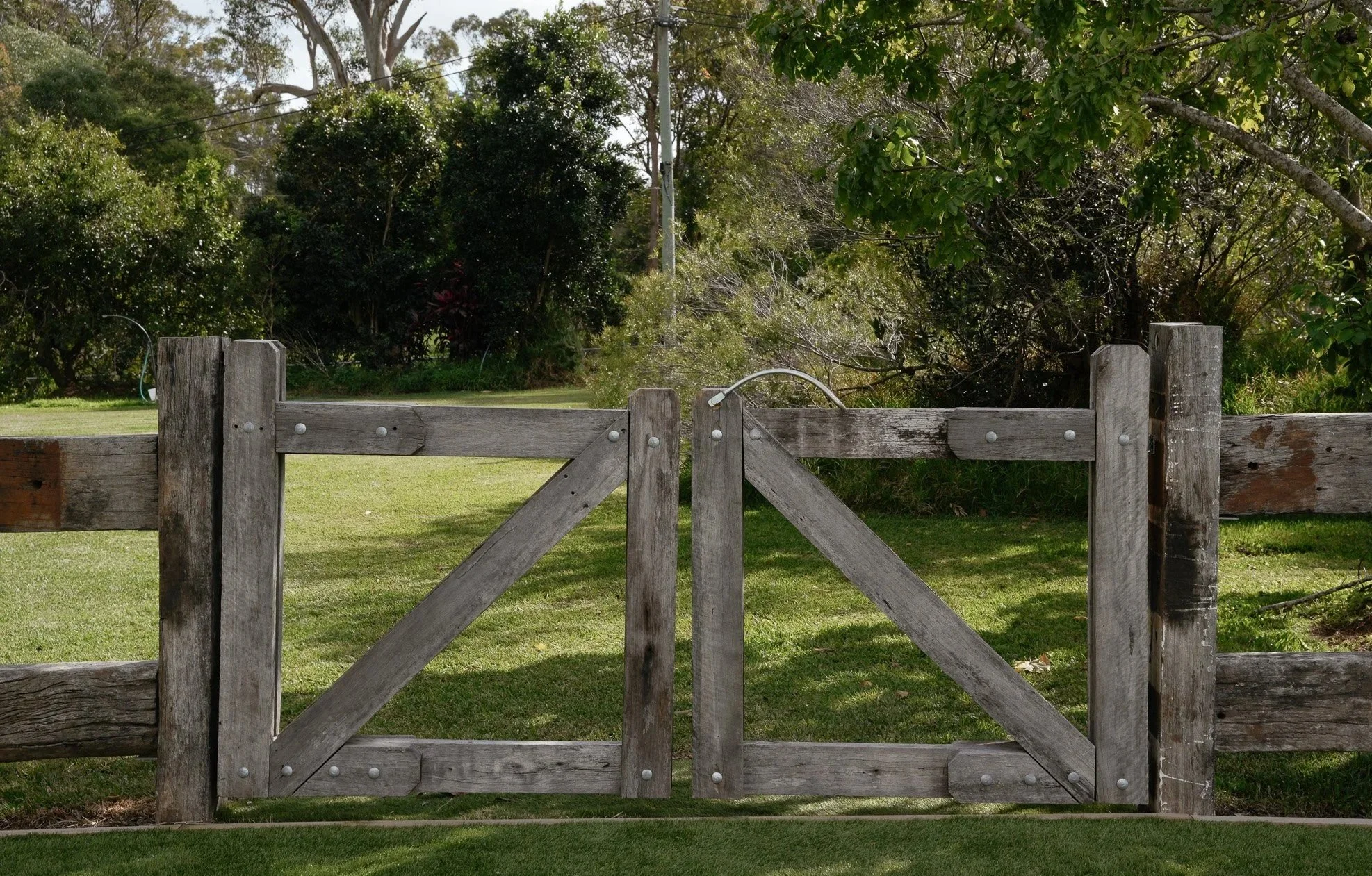 Modern white house with glass sliding doors, surrounded by a garden with green grass, small trees, and a gravel pathway leading to the entrance.