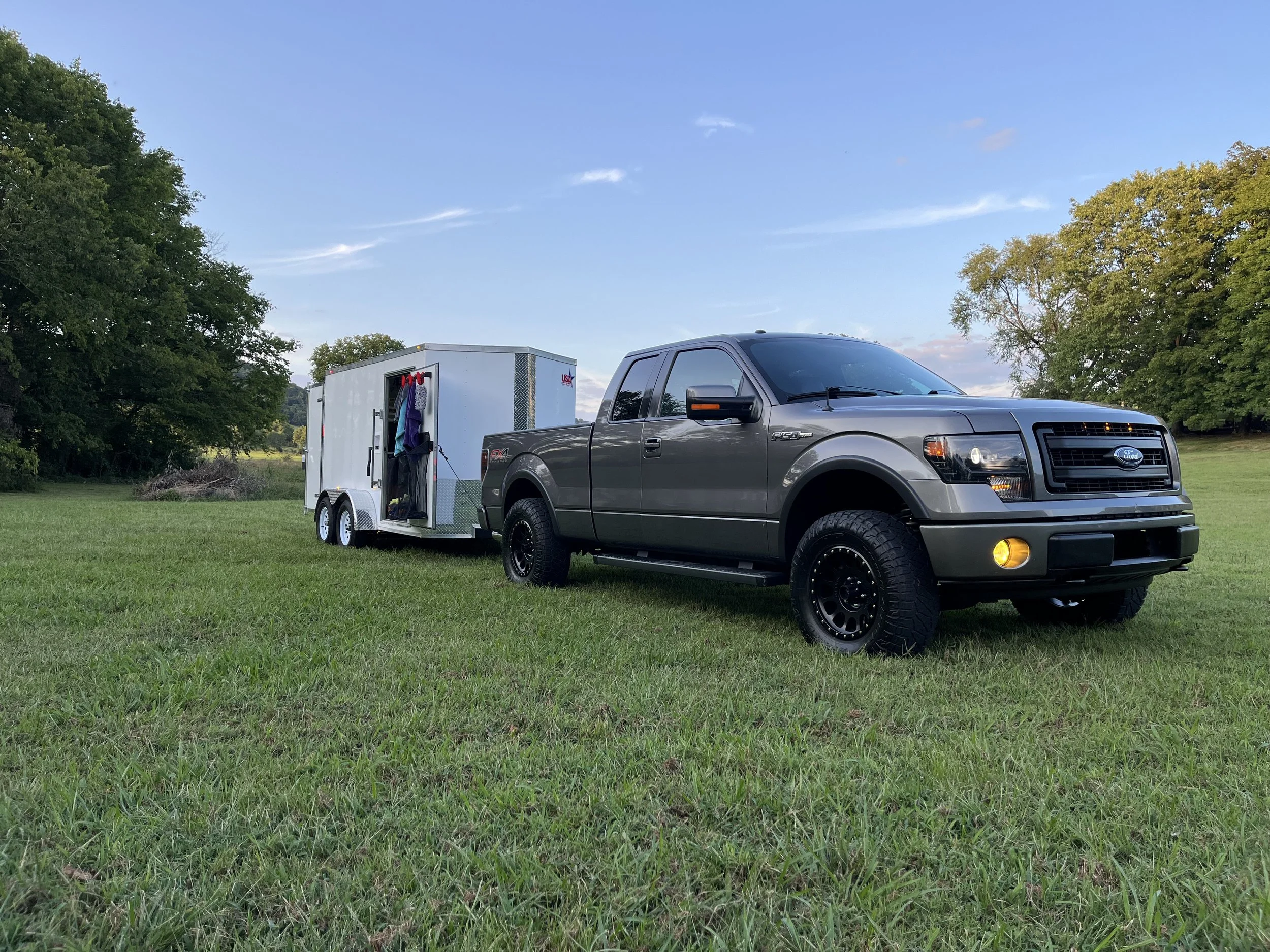 A gray Ford F-150 pickup truck towing a clean white mobile detailing trailer that has just been built to do mobile details