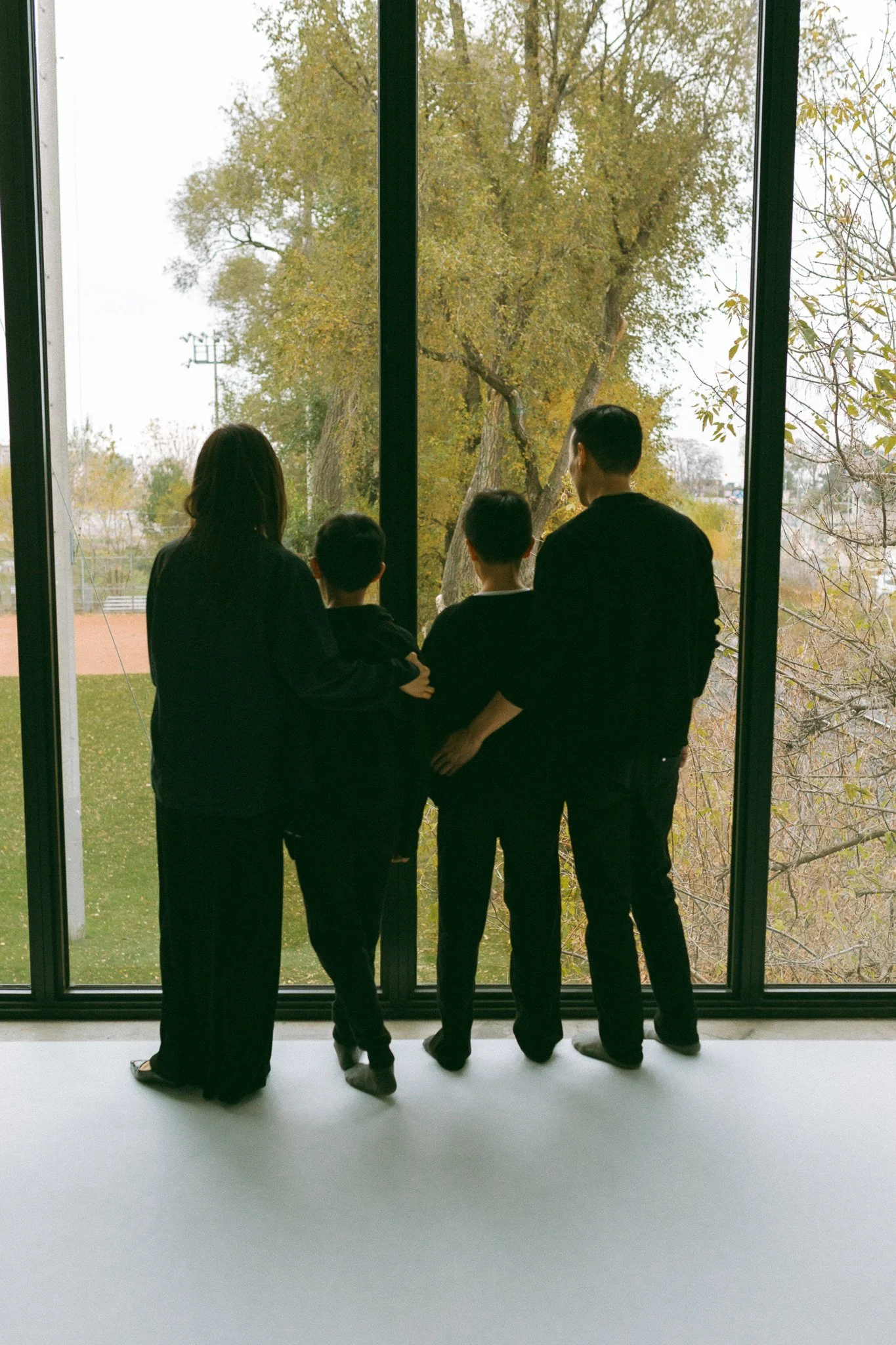 Mother, Father, and Two Sons Looking Out the Window Together