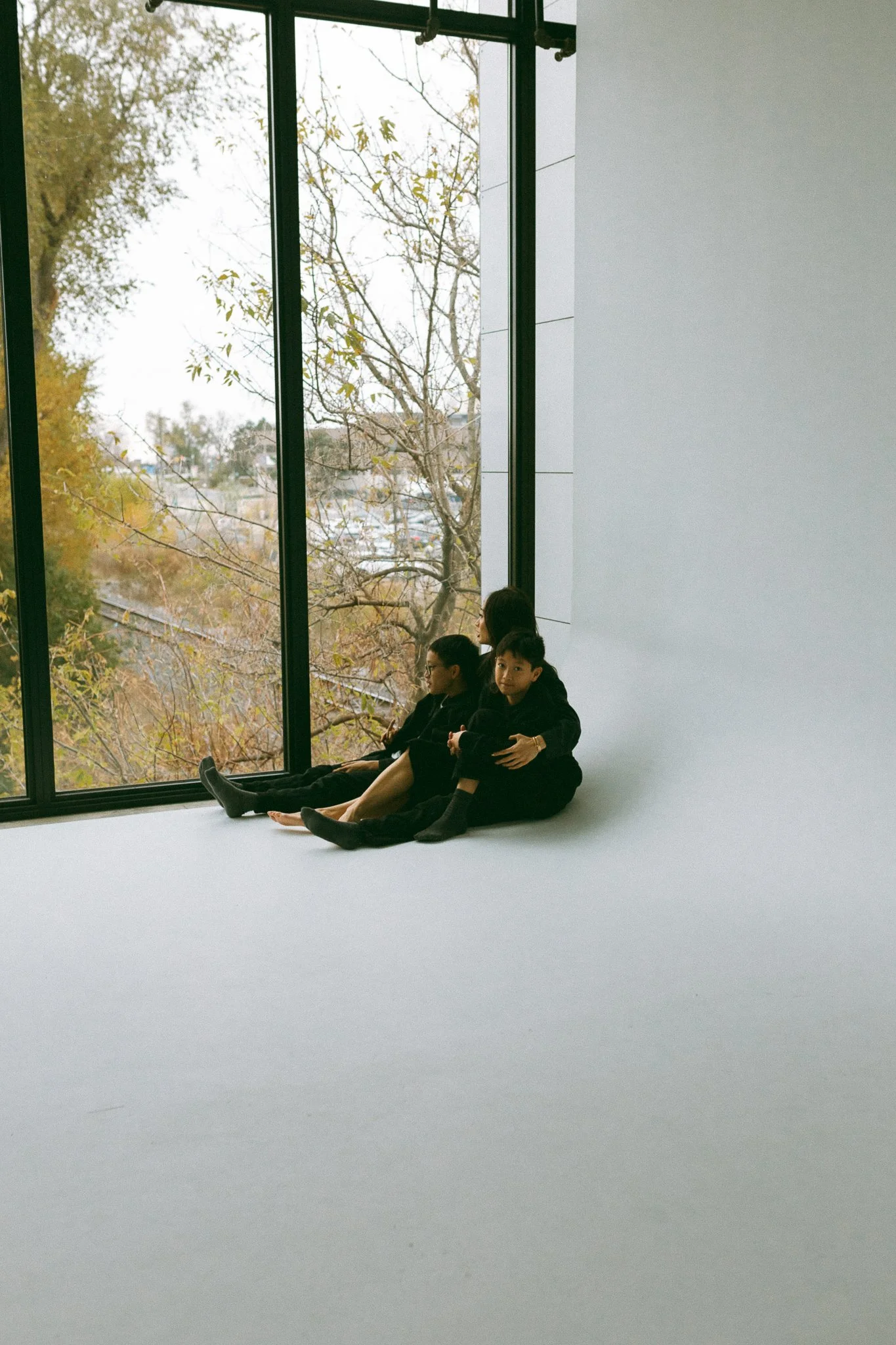 Mother and Two Sons Sitting Together, Leaning on Each Other Near Window
