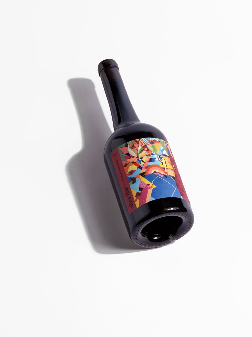 A single bottle of Alles Klar Reserva Lambrusco 2022, is shown lying diagonally on a white surface, casting a soft shadow to its left.