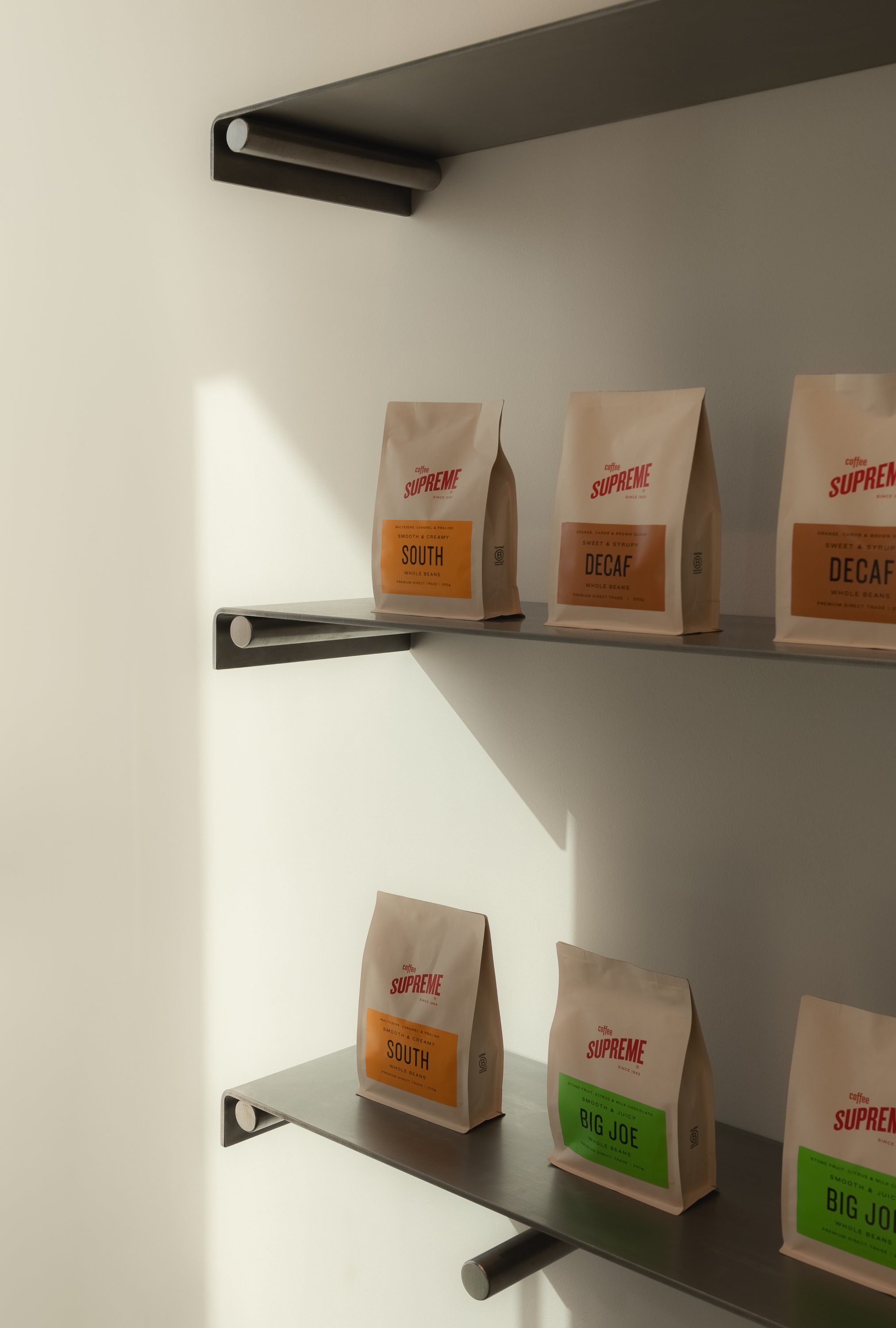 Minimal retail bakery display with custom stainless steel shelving, curated product presentation and contemporary hospitality interior detailing. 