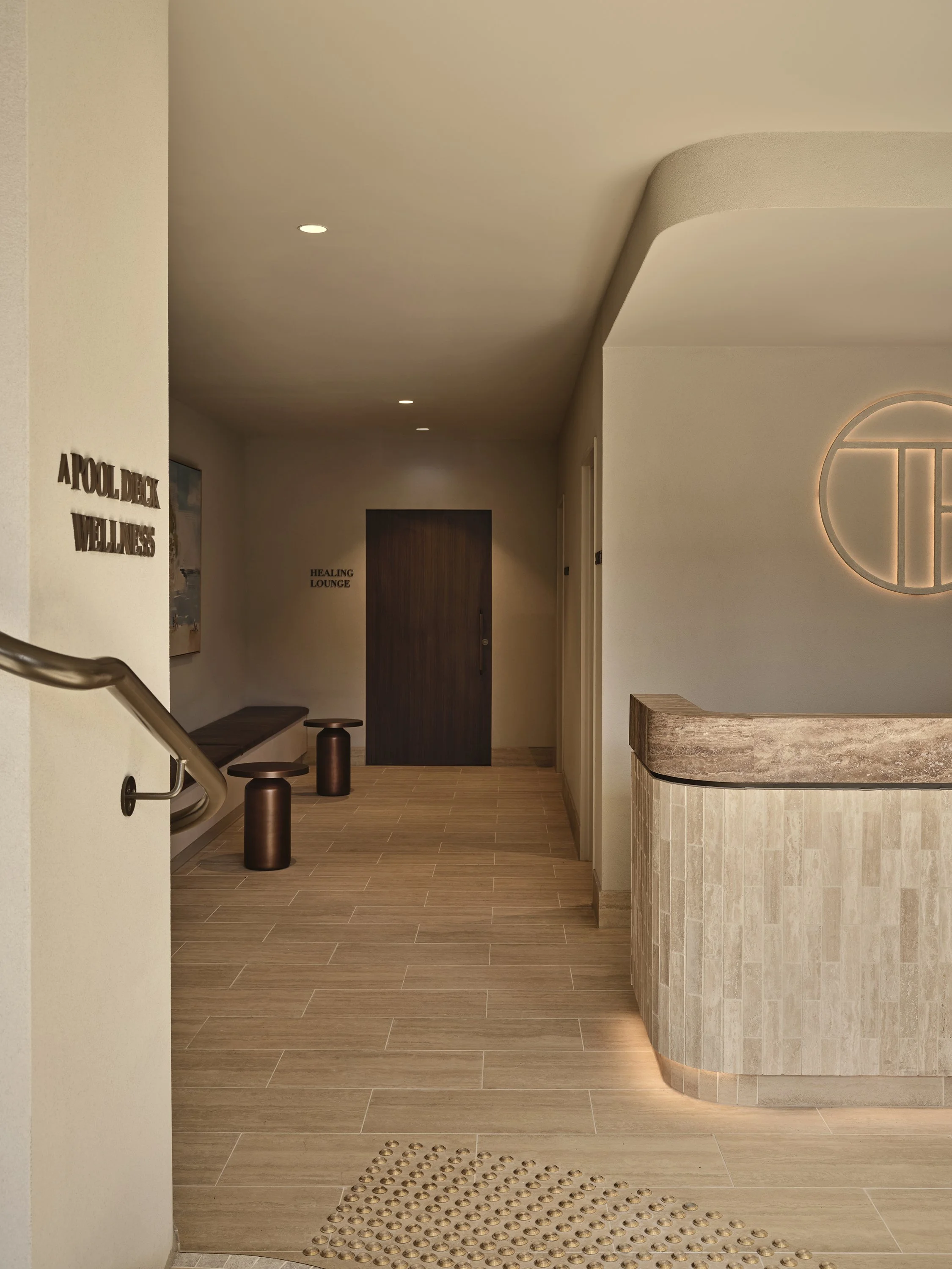 High-end wellness space in Melbourne Docklands with warm stone finishes, curved receptions and soft lighting
