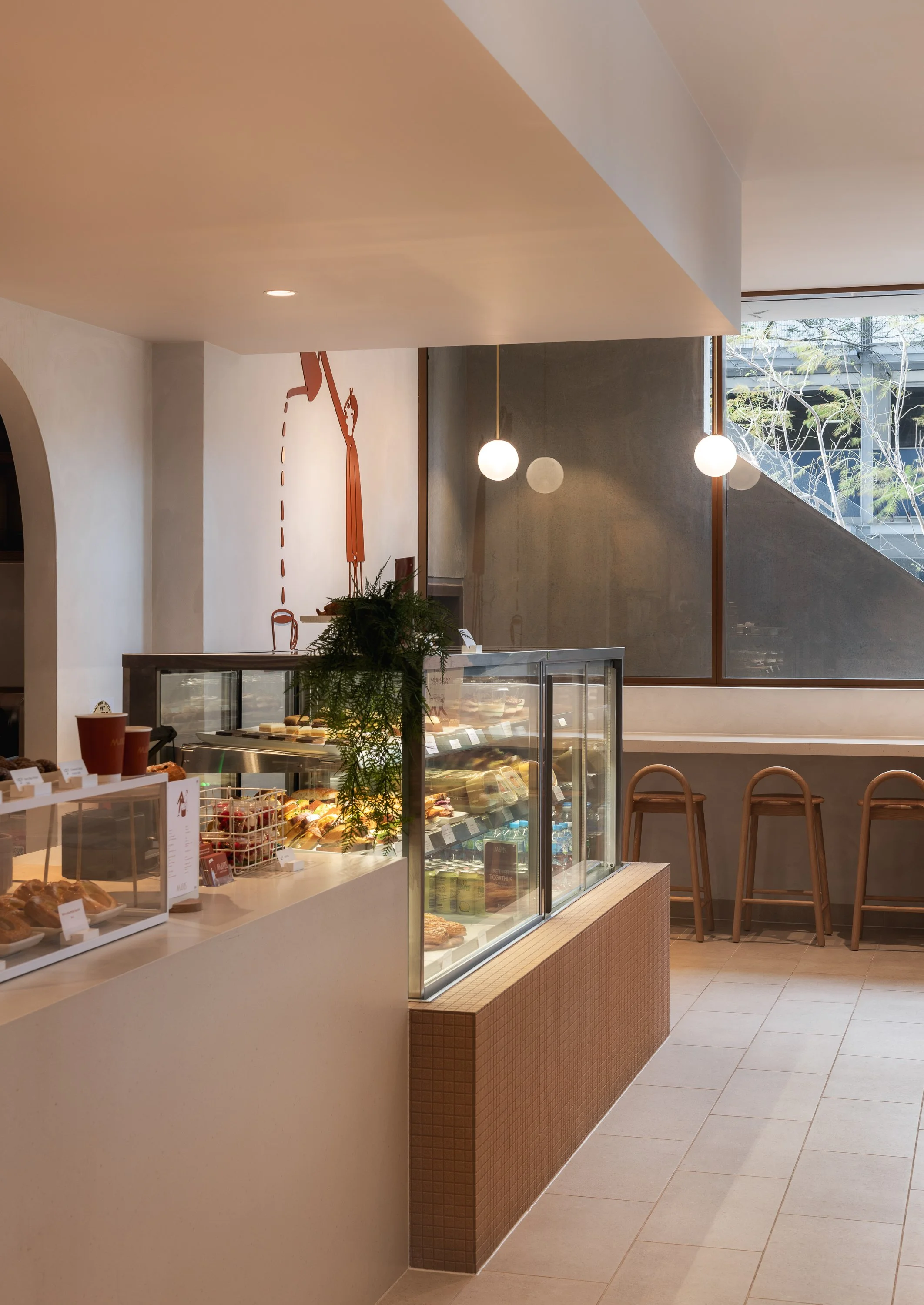 Custom cafe counter with integrated food display and warm neutral finishes.