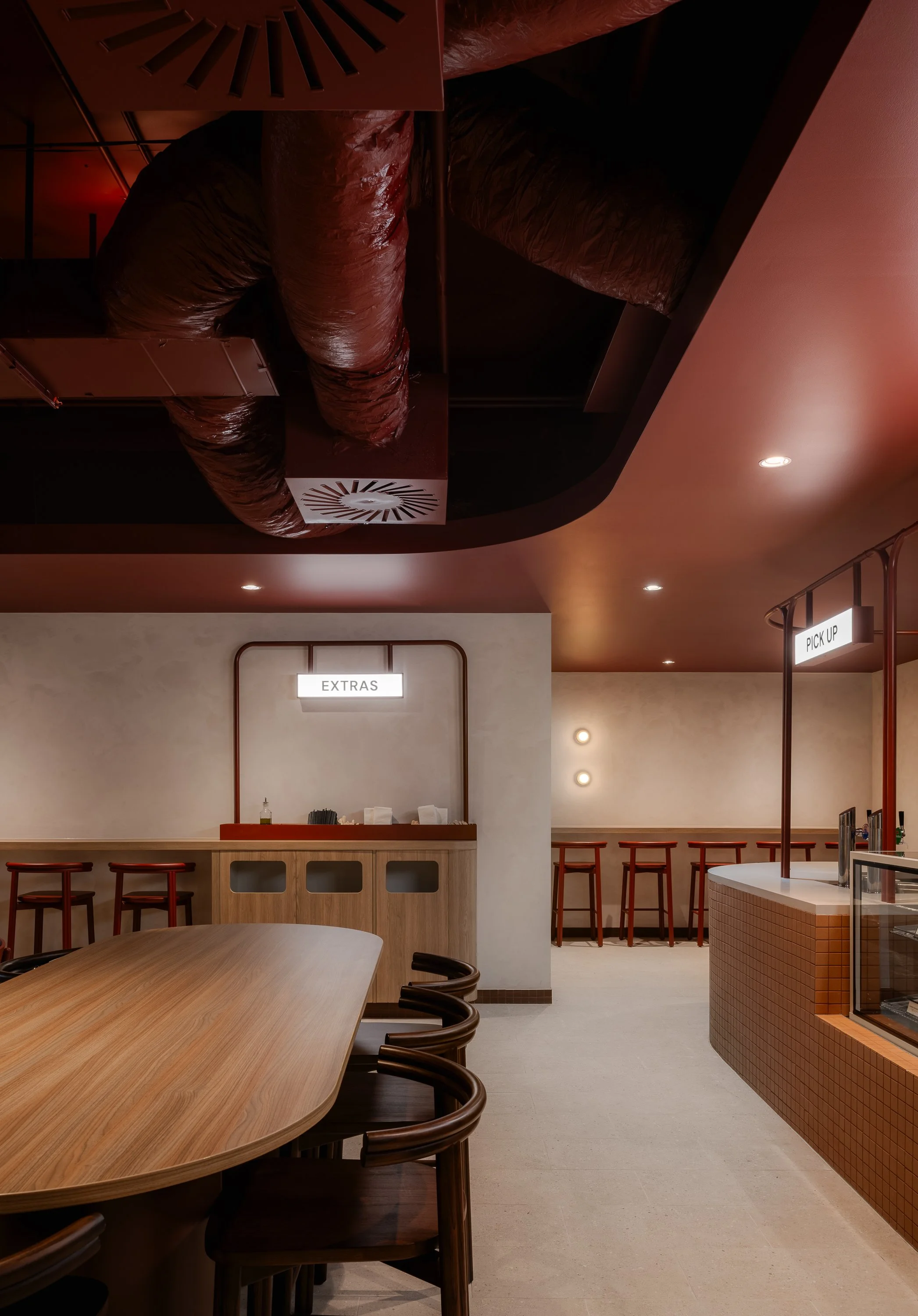Contemporary restaurant interior featuring burgundy ceilings, exposed services and timber dining furniture.