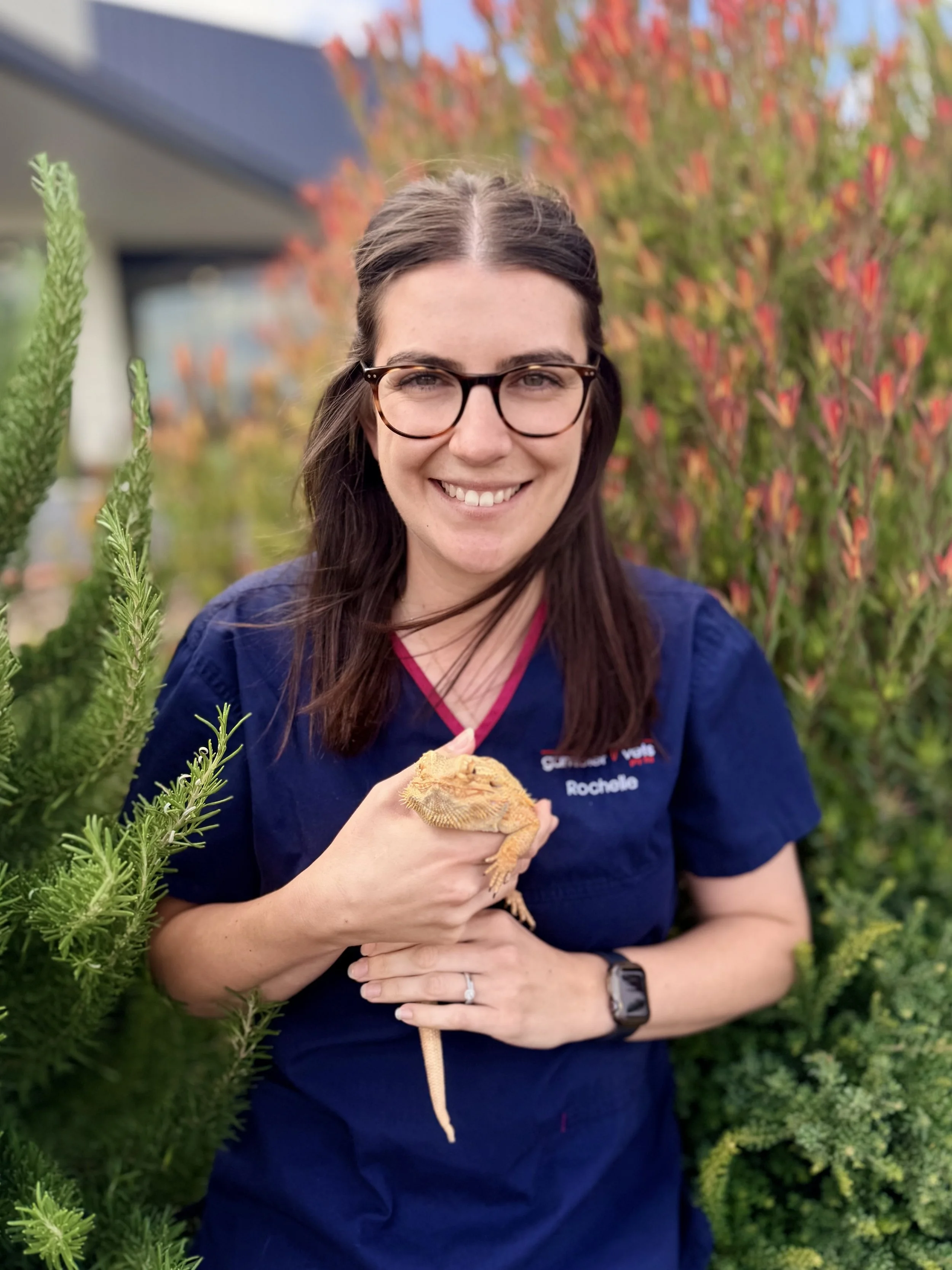 Young woman with dark hair in a high ponytail holding a small orange and white kitten, both smiling.