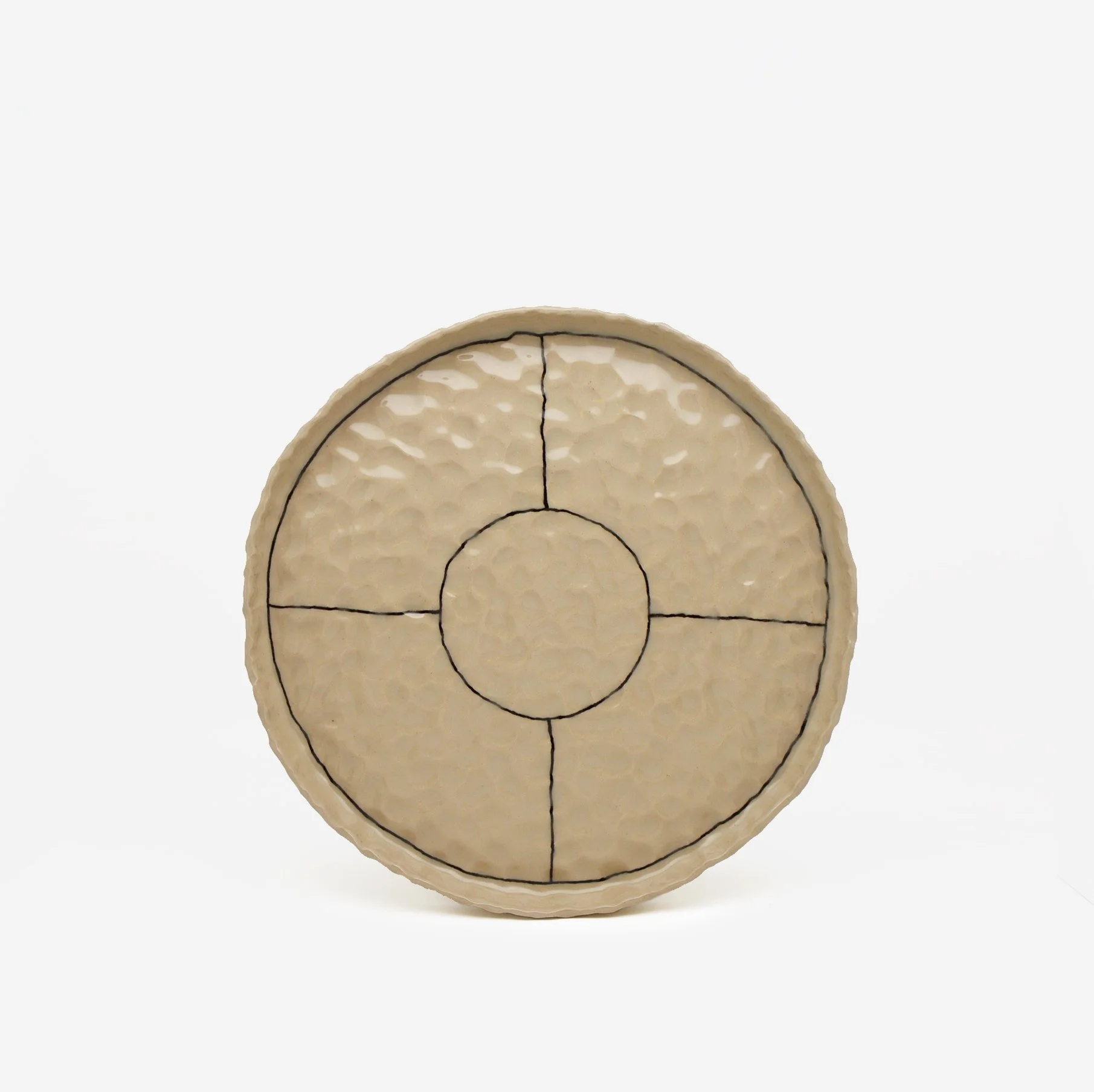 A stoneware pinched plate with black outline markings. The background is plain white.