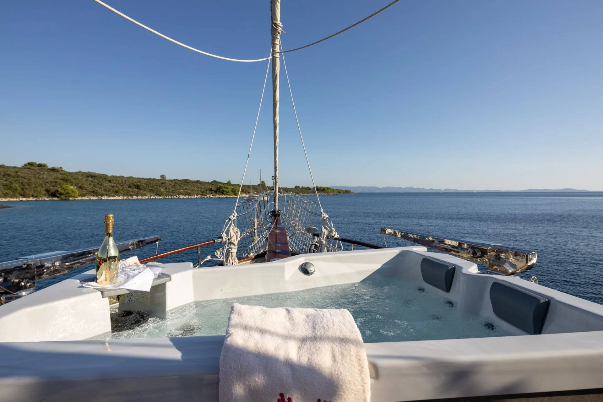 Hot tub on a yacht with champagne bottle, towel, and ocean view