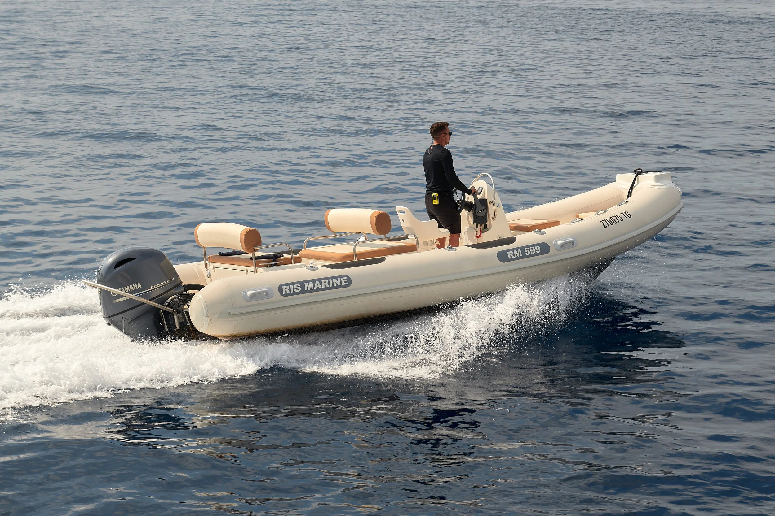 A man steering a small inflatable boat with Yamaha outboard motor on a calm body of water.