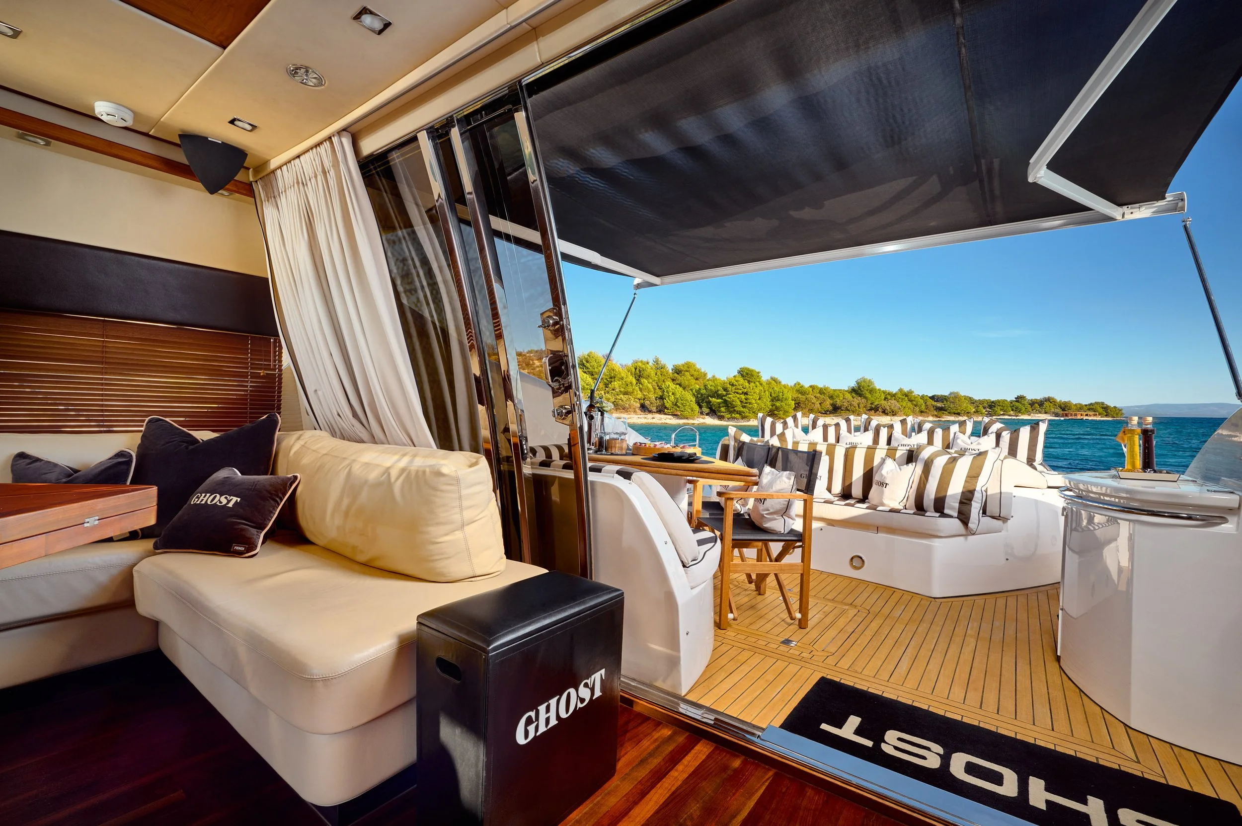 Interior of a yacht with a view of the deck and ocean outside, including seating and a small table.