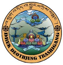 The image features a circular emblem with colorful art depicting three multi-colored lotus flowers and a background of blue sky, mountains, and water. The outer border has Tibetan script and the words 'Druk Deothung Tashi Ghang' at the bottom.
