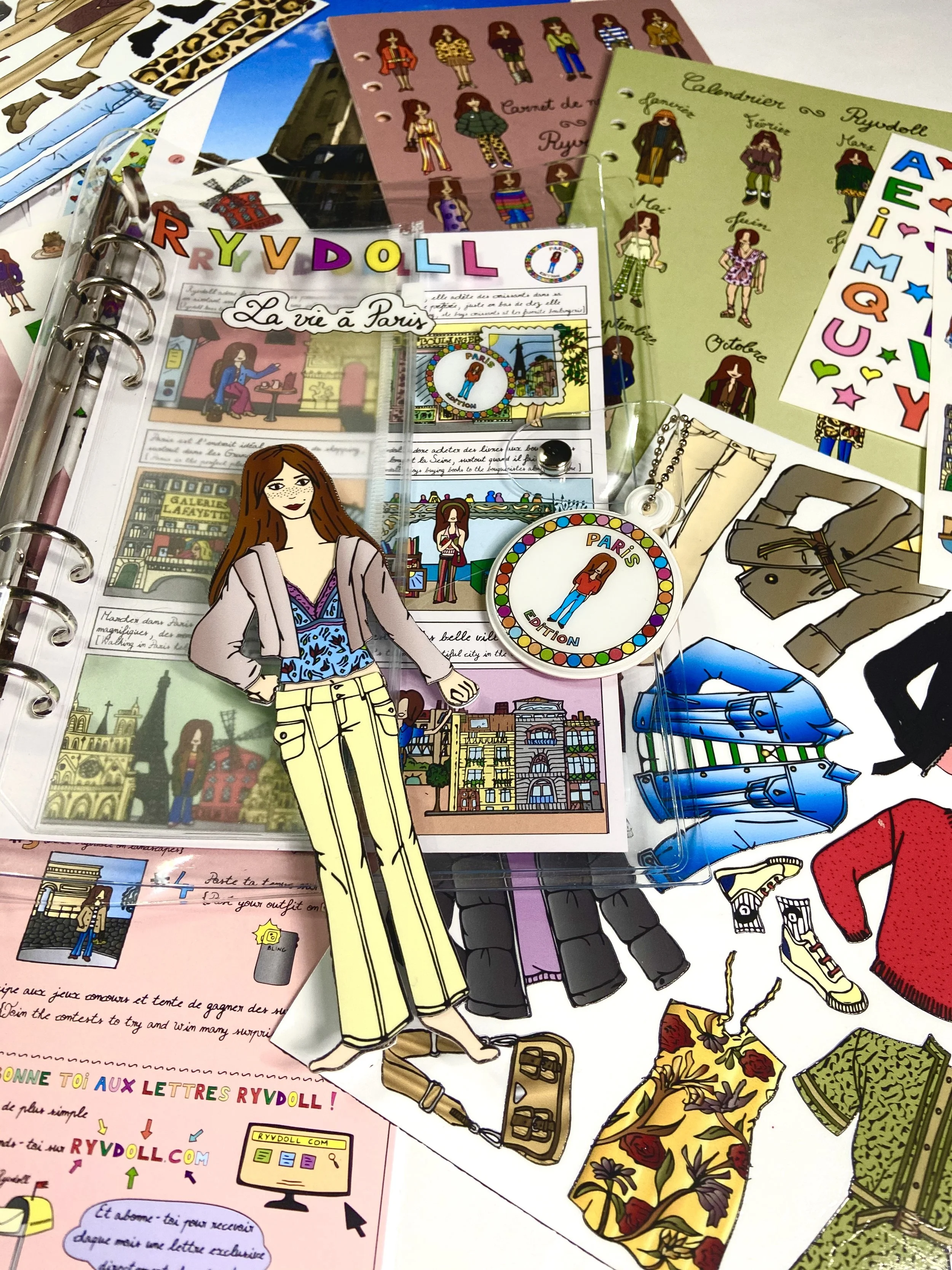 A colorful collection of Paris-themed stickers, postcards, and postcards featuring fashion, landmarks, and illustrations of women, along with a paper doll and jewelry.