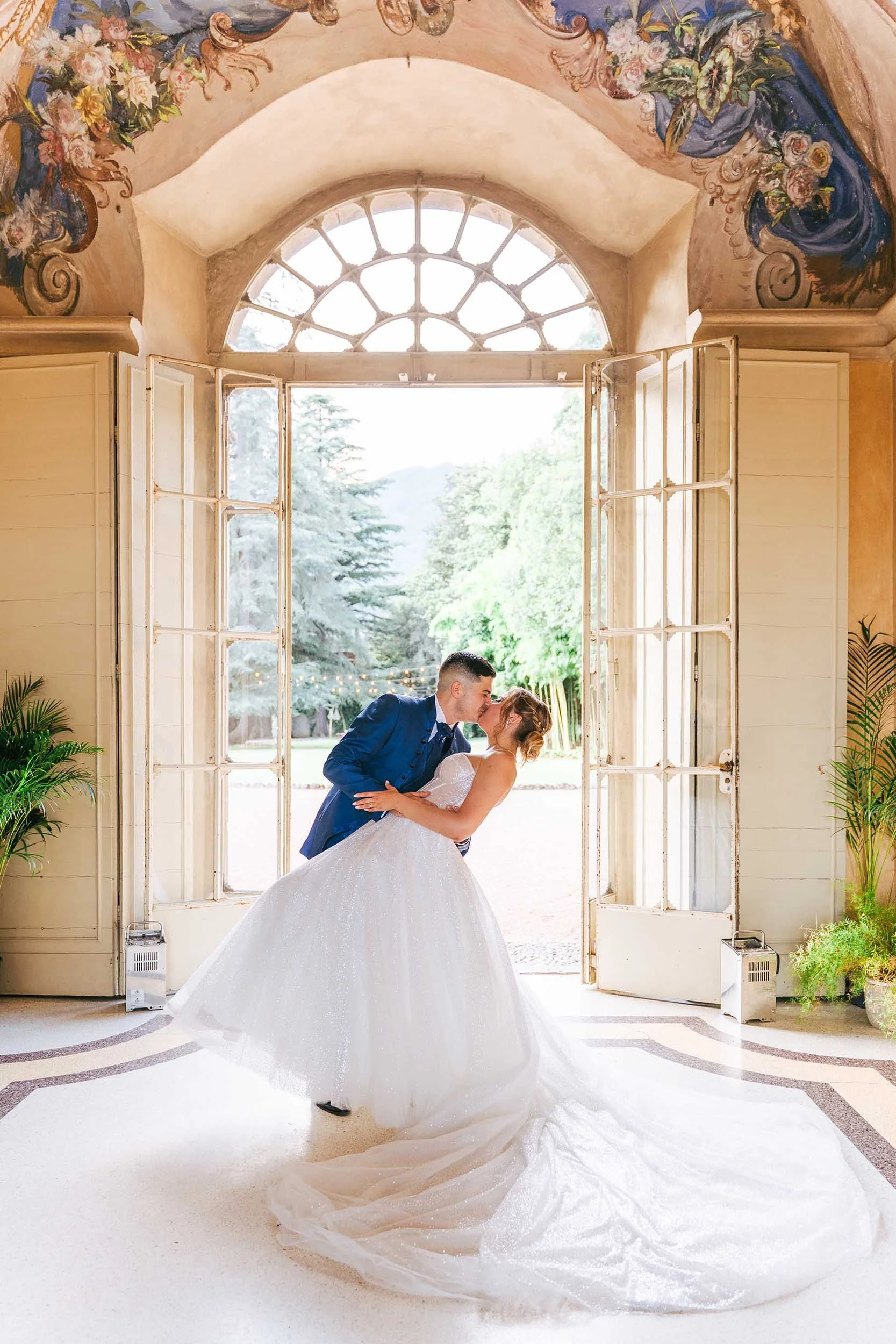 Gli sposi si baciano all'ingresso della villa sotto un magnifico affresco