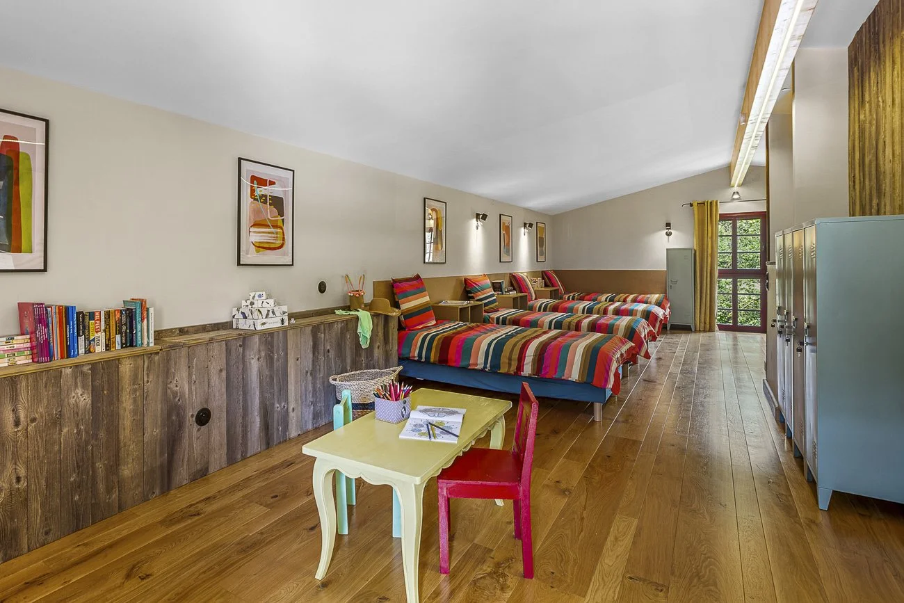 Room with multiple colorful striped beds and a small table with chairs.