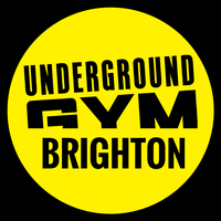 Bright yellow circular sign with black text displaying 'Underground Gym Brighton'.