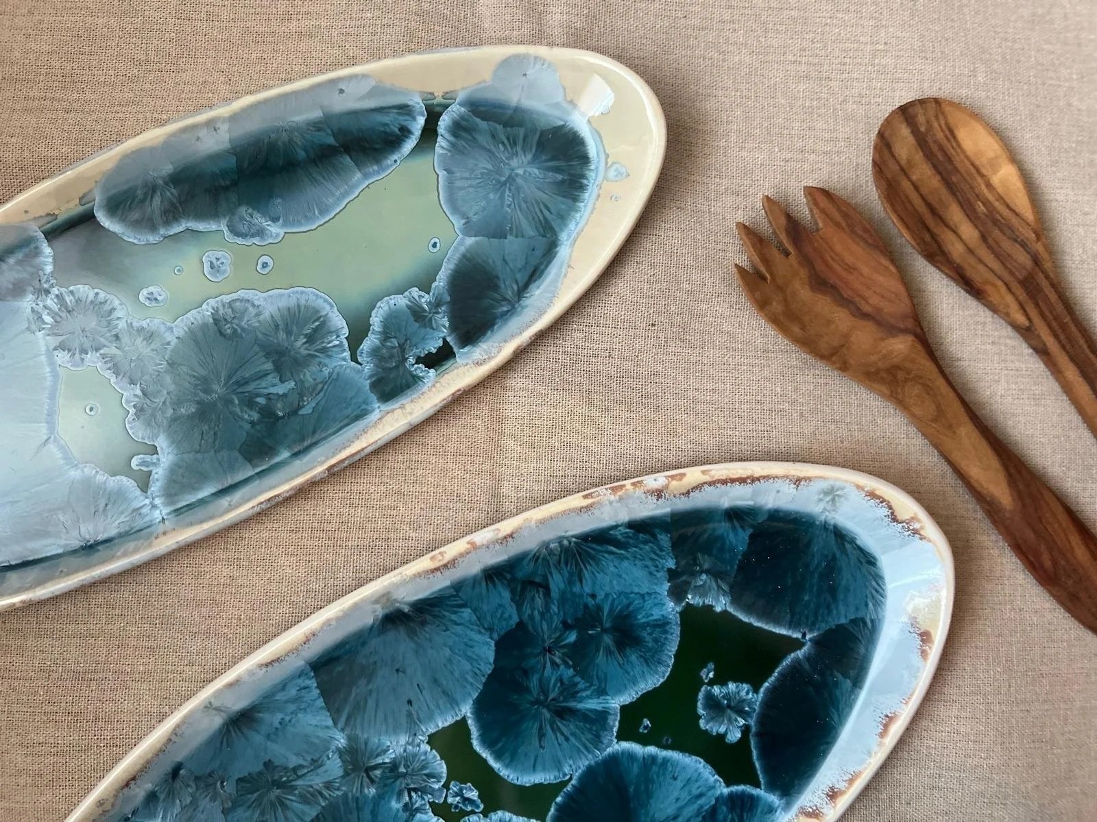 Two oval ceramic plates with blue crystals bloom upon porcelain, born of fire and minerals, a secret dance of earth, water, air and the ceramist’s spirit.