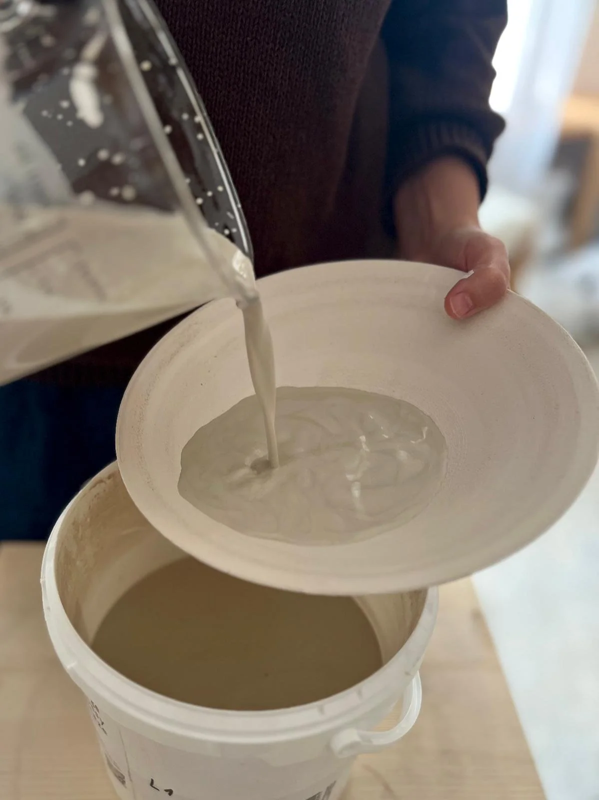A ceramist applying glaze to a piece.