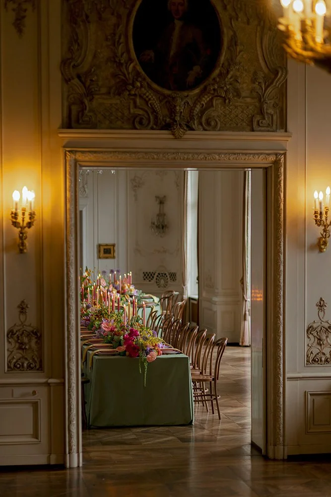 In einem alten Raum hinter einem Durchgang steht ein Tisch mit Blumen und Kerzen.